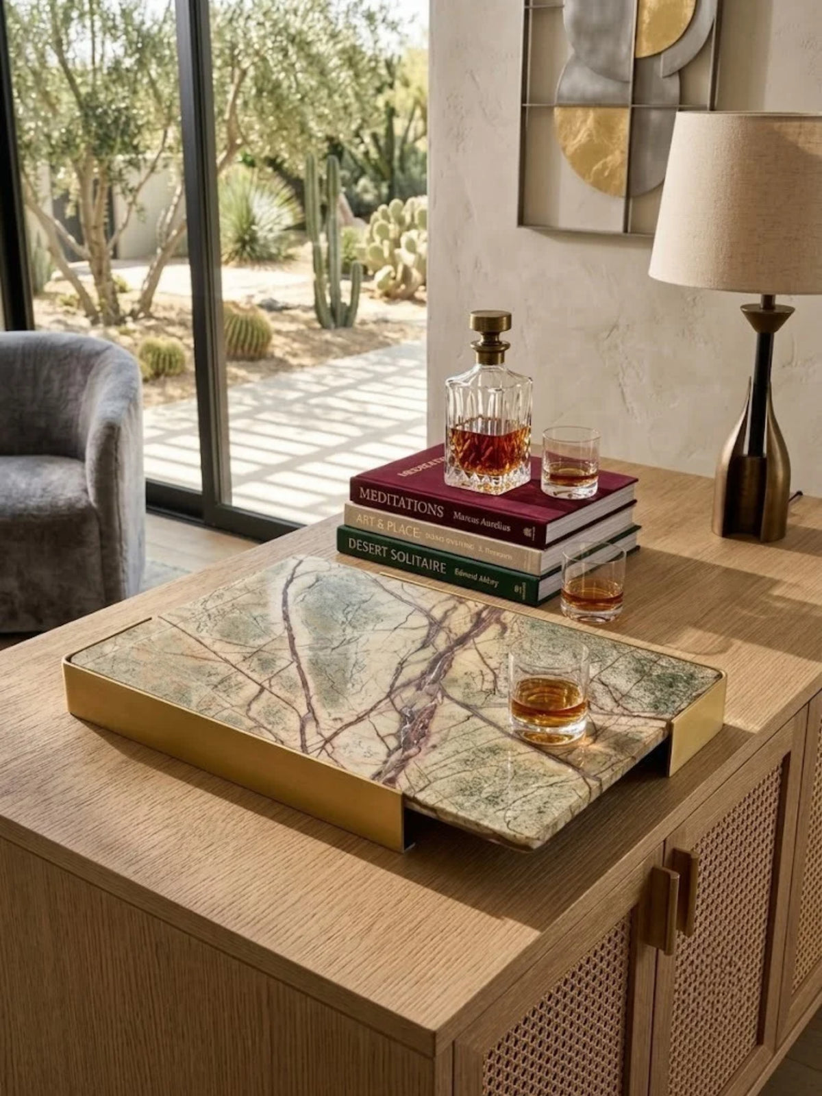 Normandy onyx marble tray holding a whiskey decanter and books at a home bar.