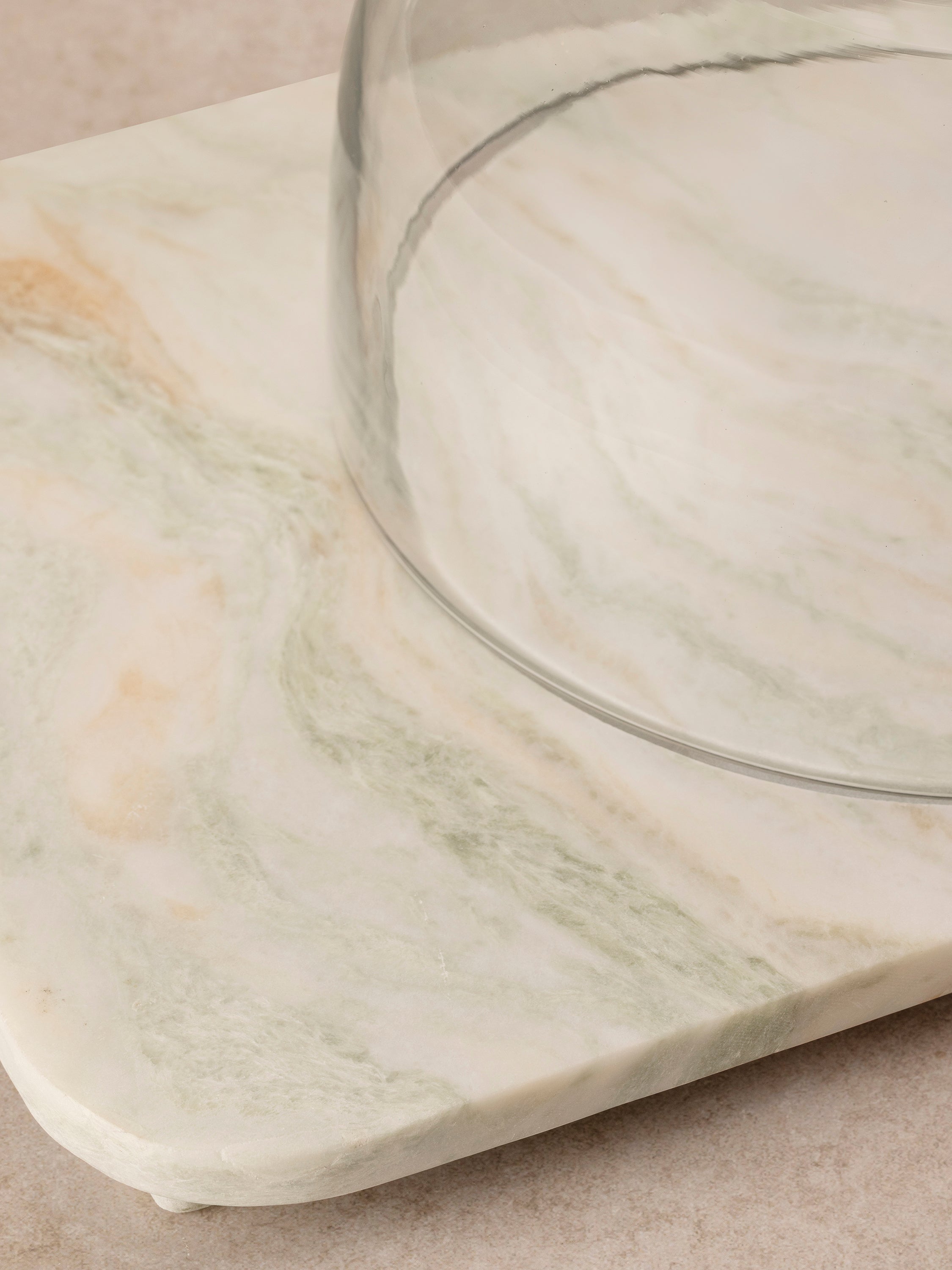 Close-up of the Moonlight onyx cloche board showing stone surface detail, soft green mineral movement, and edge profile beneath the dome.