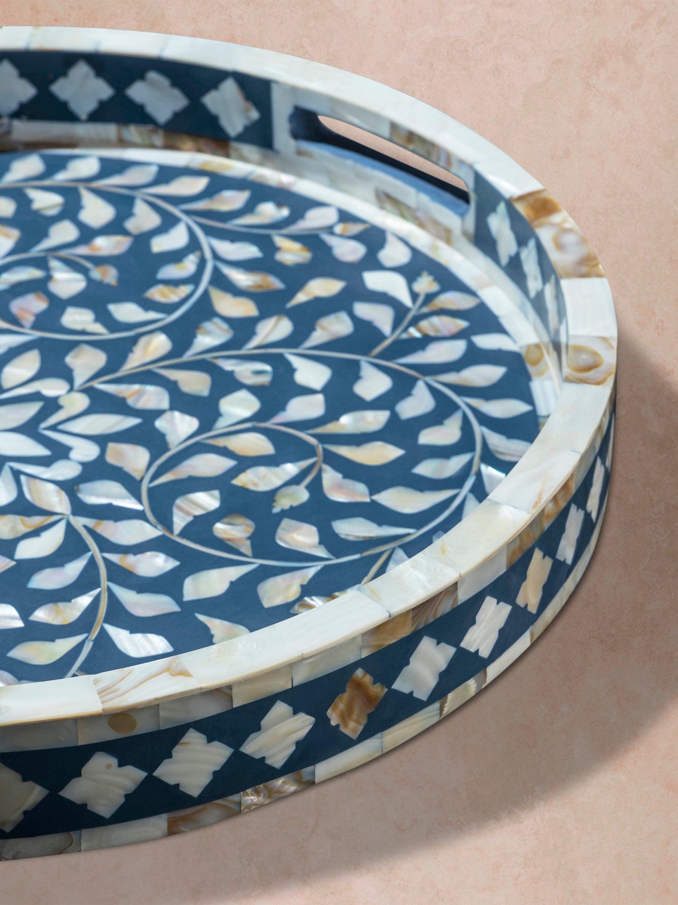Close-up of blue inlay tray showing carved edge profile, inlaid rim, and layered floral pattern across the surface