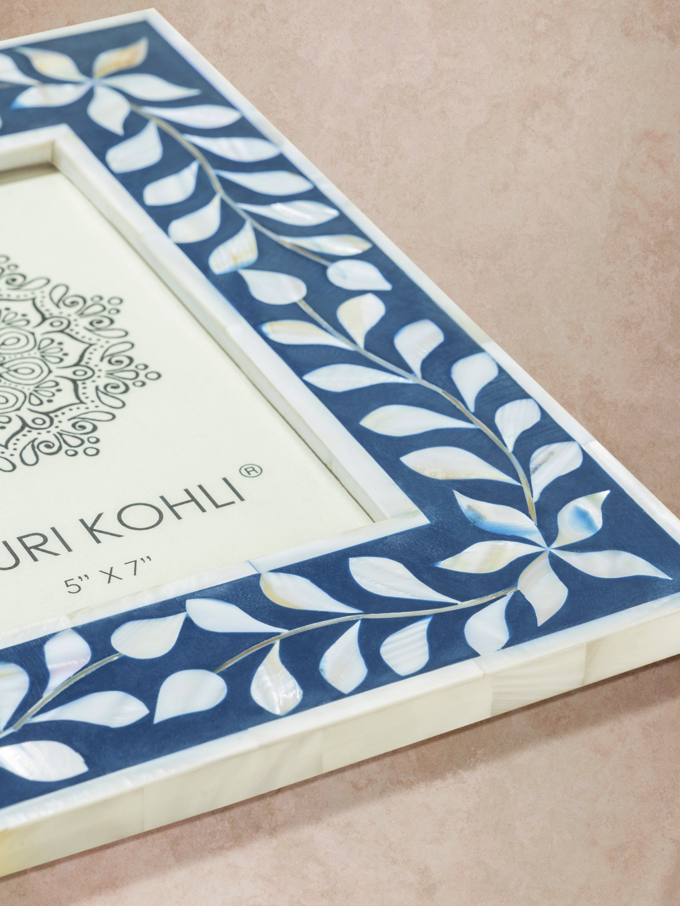 Close-up of blue inlay picture frame showing precise bone segments, geometric edge alignment, and polished surface texture