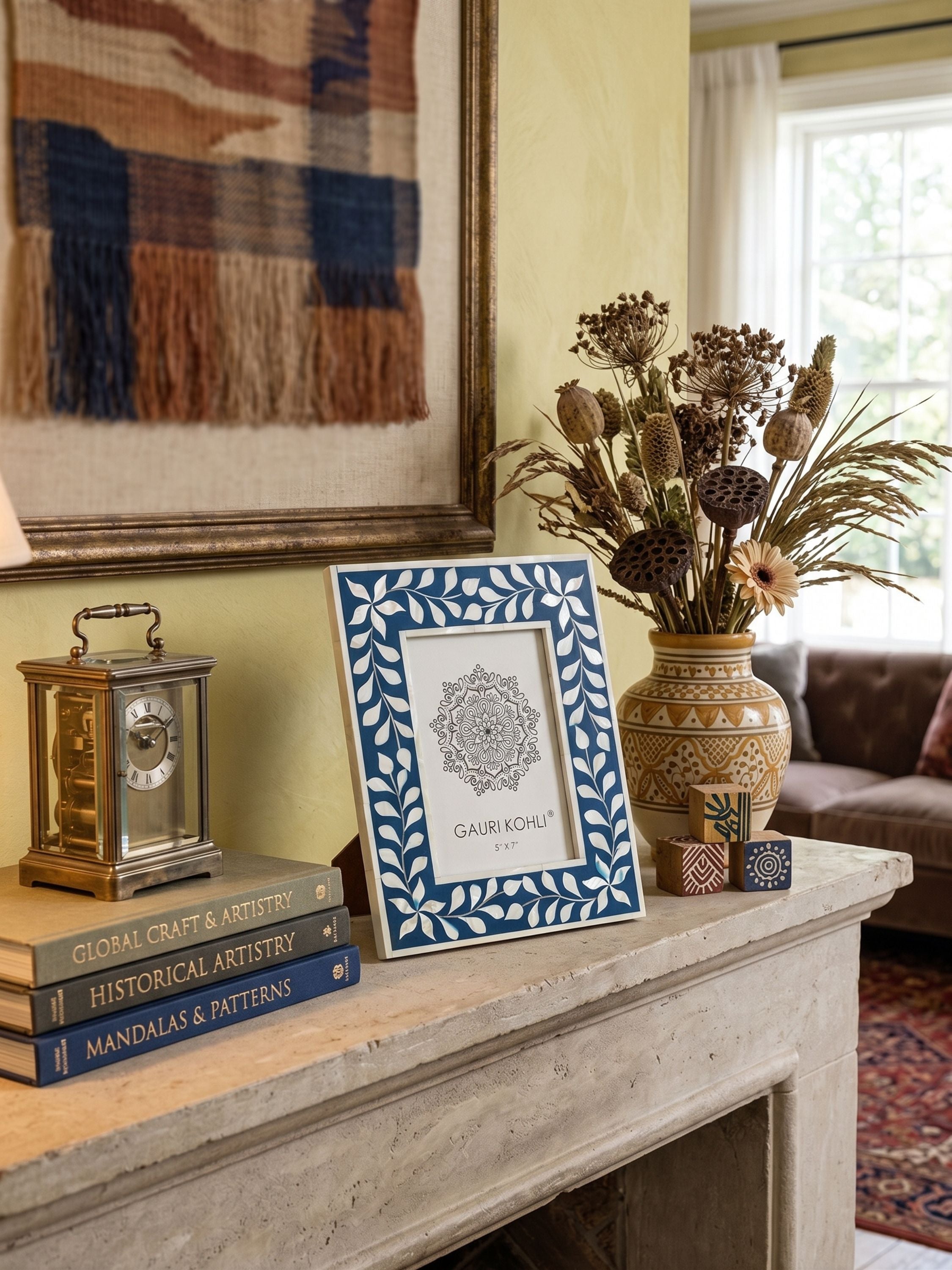 Mother of pearl and blue inlay tabletop photo frame styled on a mantel with books, clock, and decorative vase