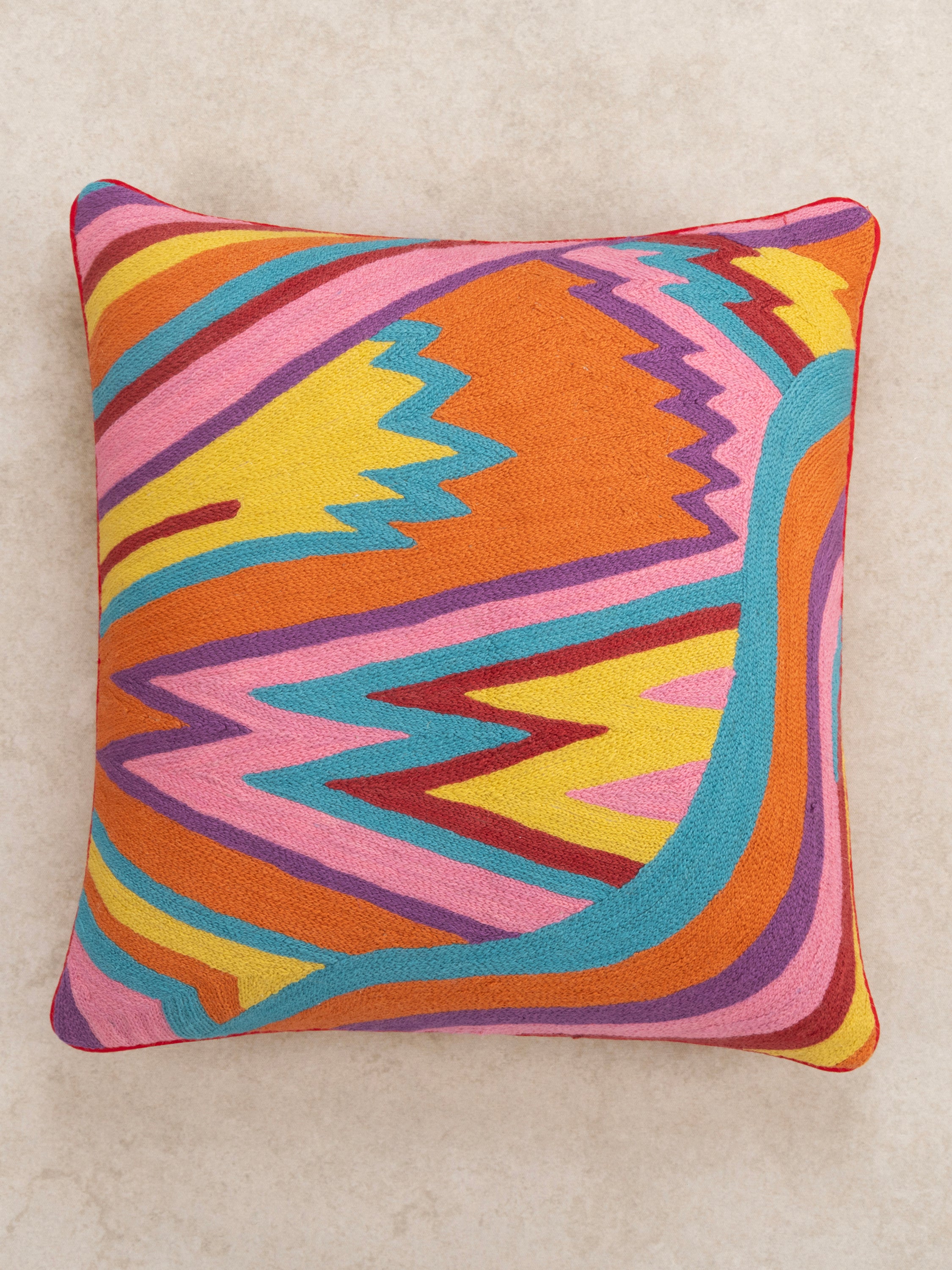 Decorative 20″×20″ pillow in natural cotton featuring bold raised embroidery in orange, pink, blue and yellow — refined home décor piece