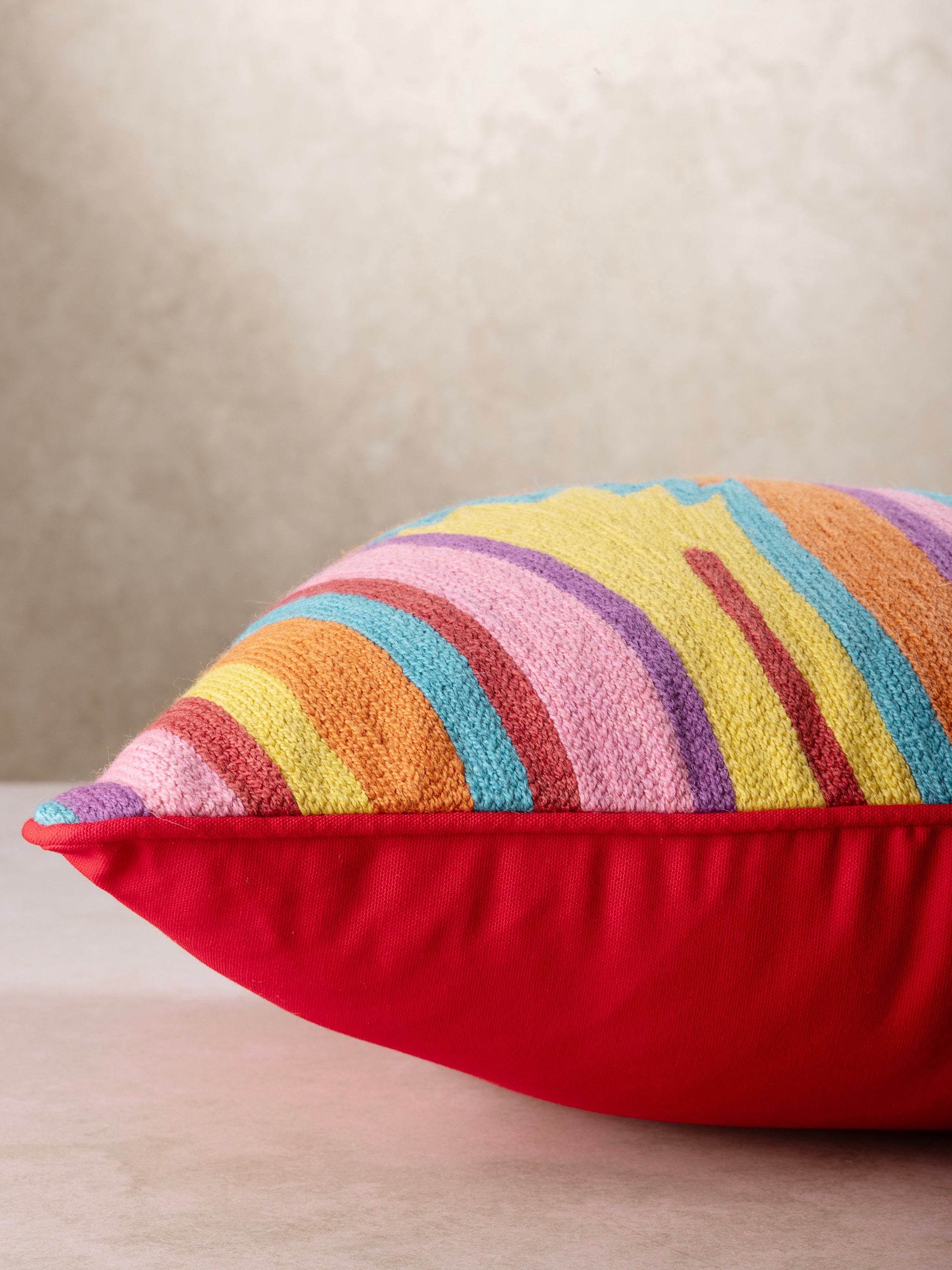 Side profile of the Ramona throw pillow showing its plush filled structure, soft rounded edges, and contrast between embroidered front and backing.