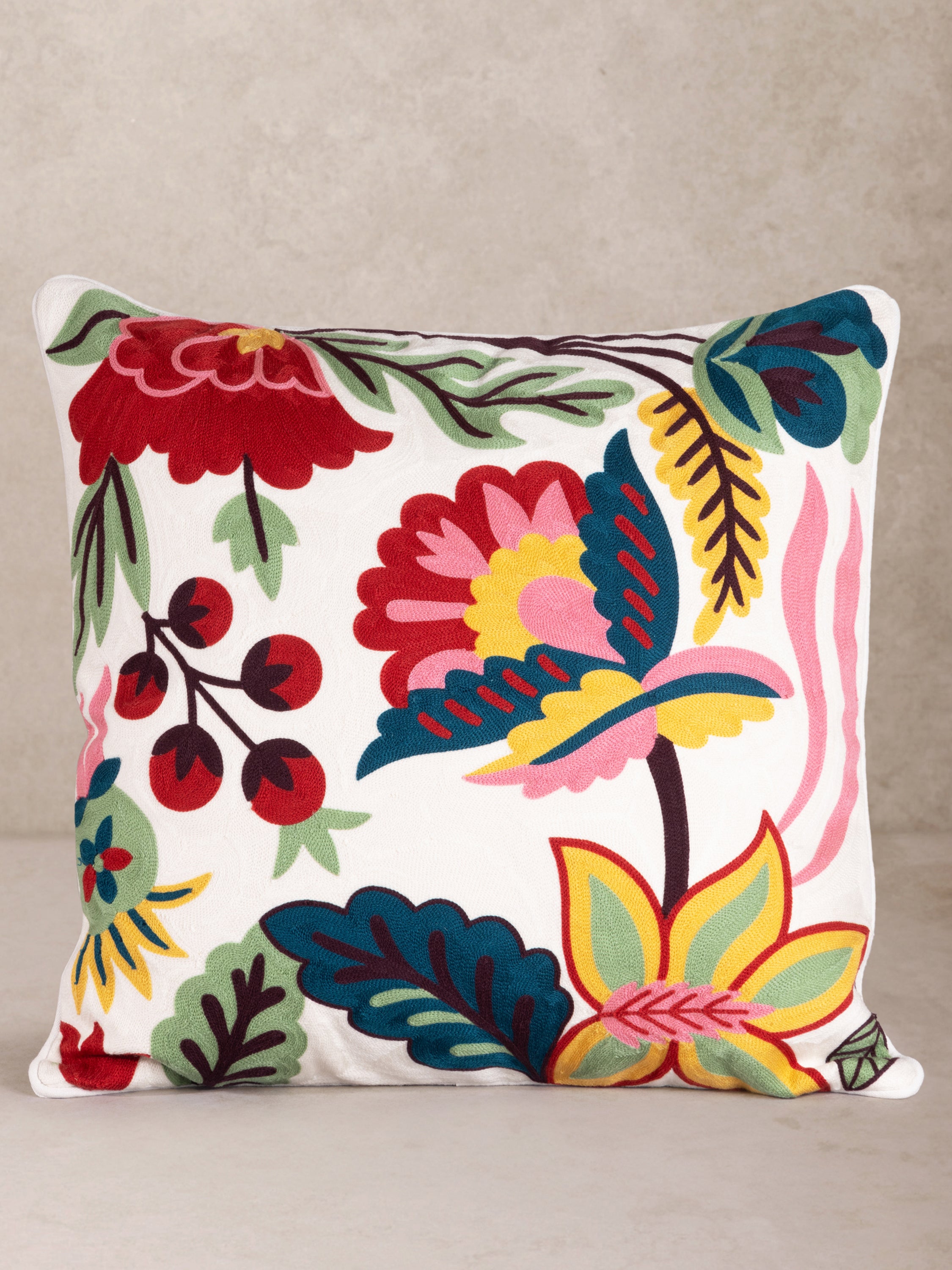 Handcrafted cotton throw pillow with vivid floral embroidery in reds, yellows and blues — artisan luxury accent