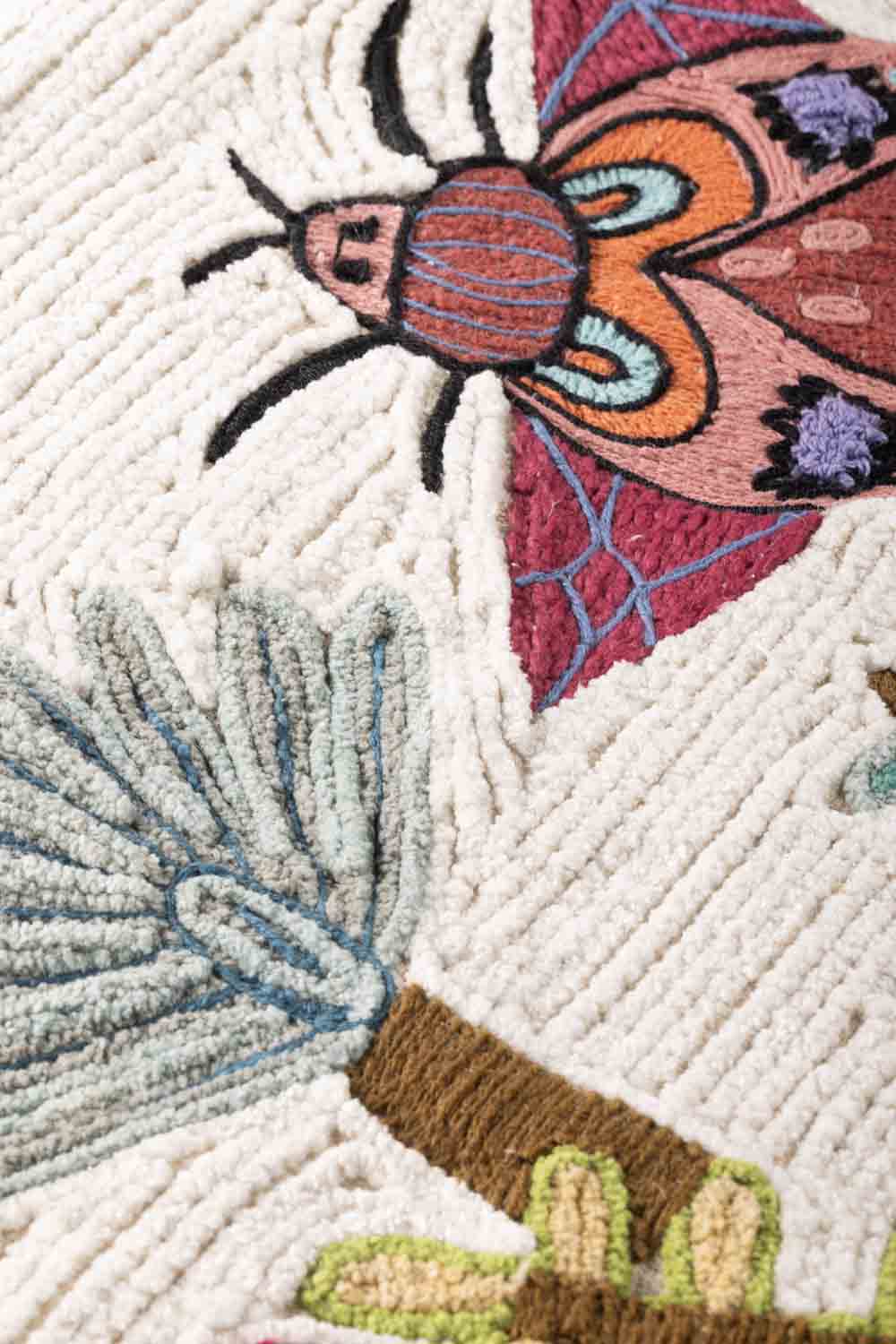 Close-up of embroidered cotton surface highlighting fine stitched outlines, selective filled elements, and subtle color variation across the textile ground