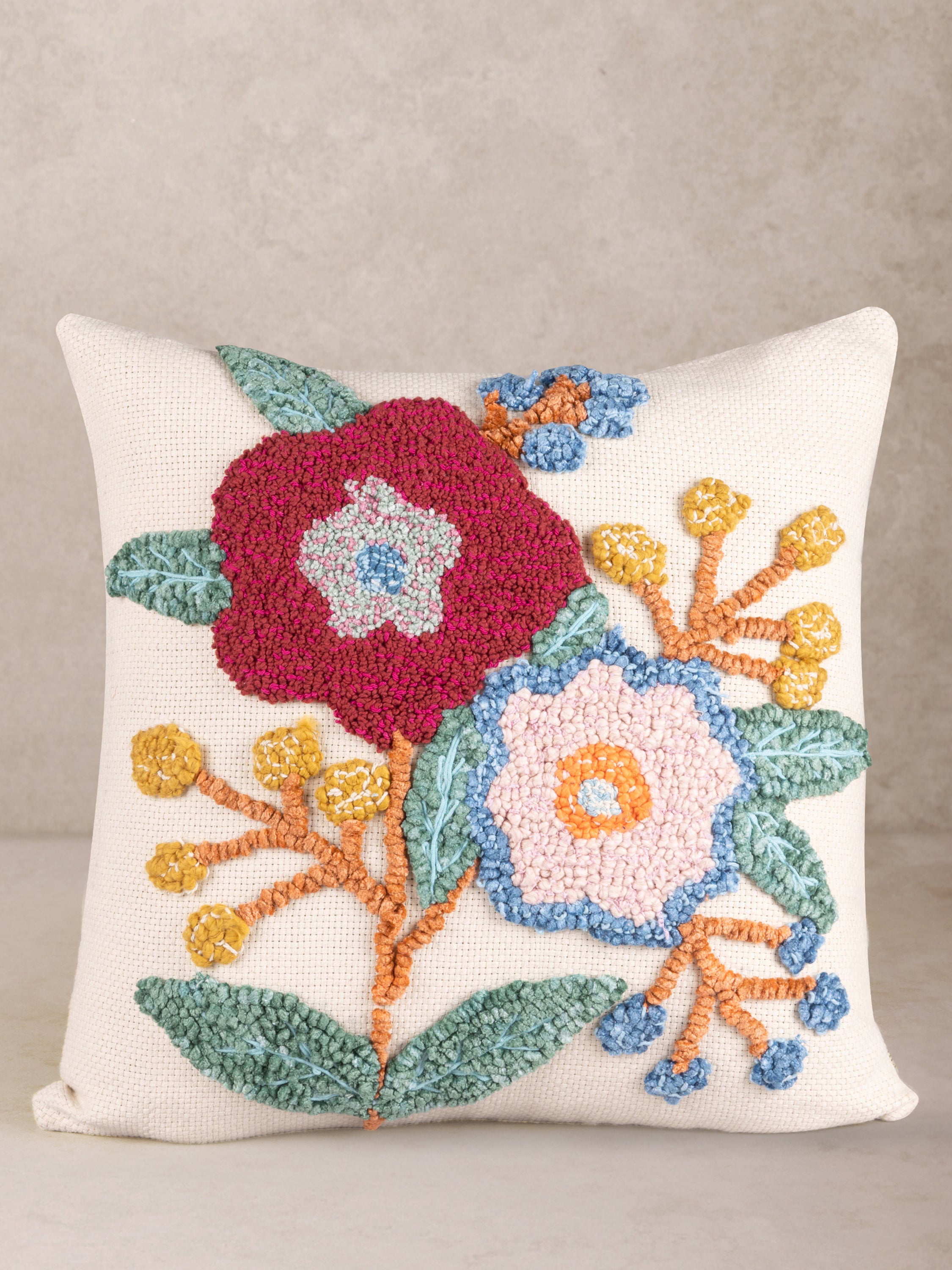 Handcrafted cotton throw pillow with raised floral-inspired embroidery in burgundy, pink and blue — artisan luxury accent
