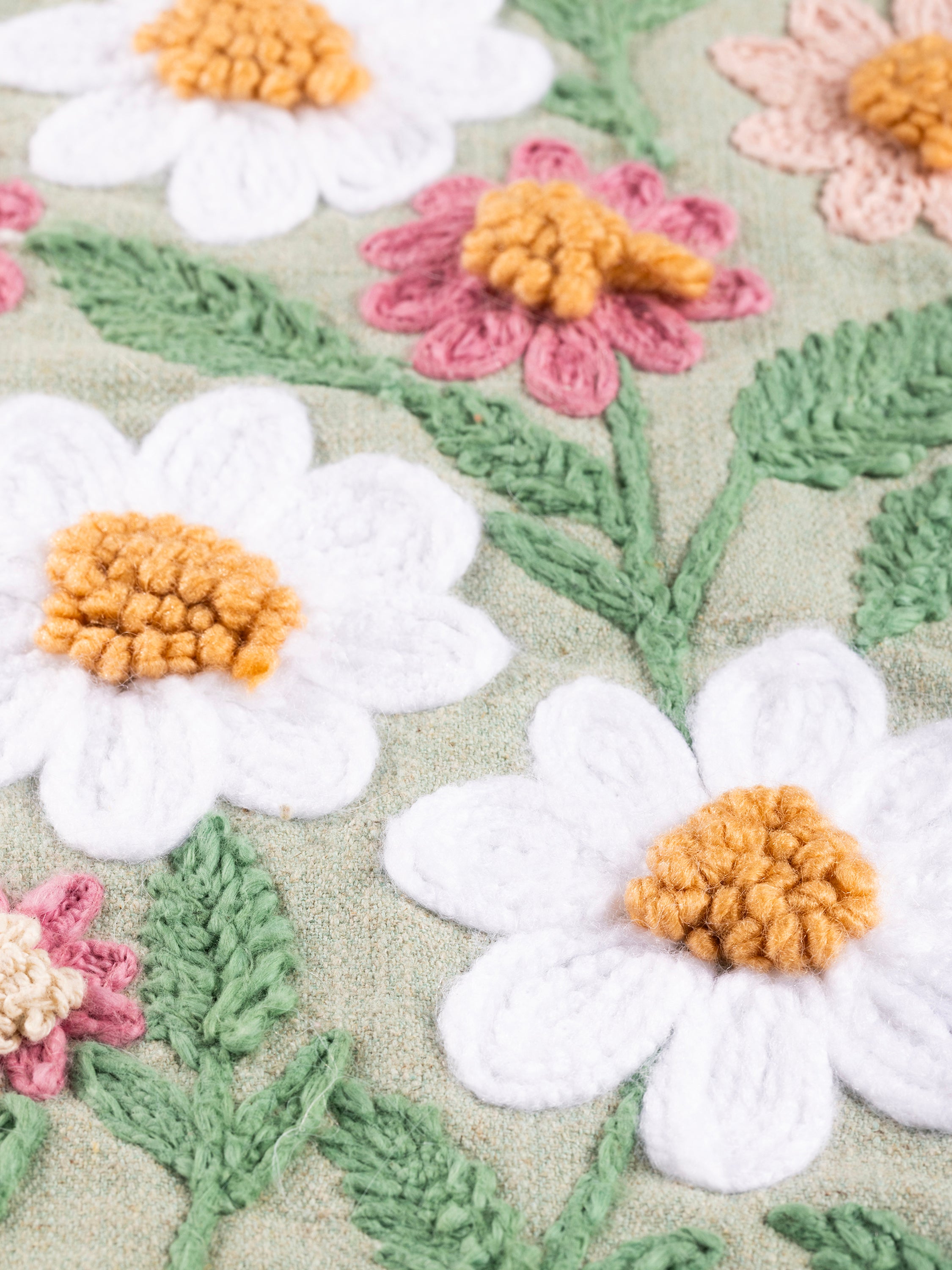 Decorative cotton throw pillow with hand-embroidered daisies in blush and white tones — handcrafted design accessory