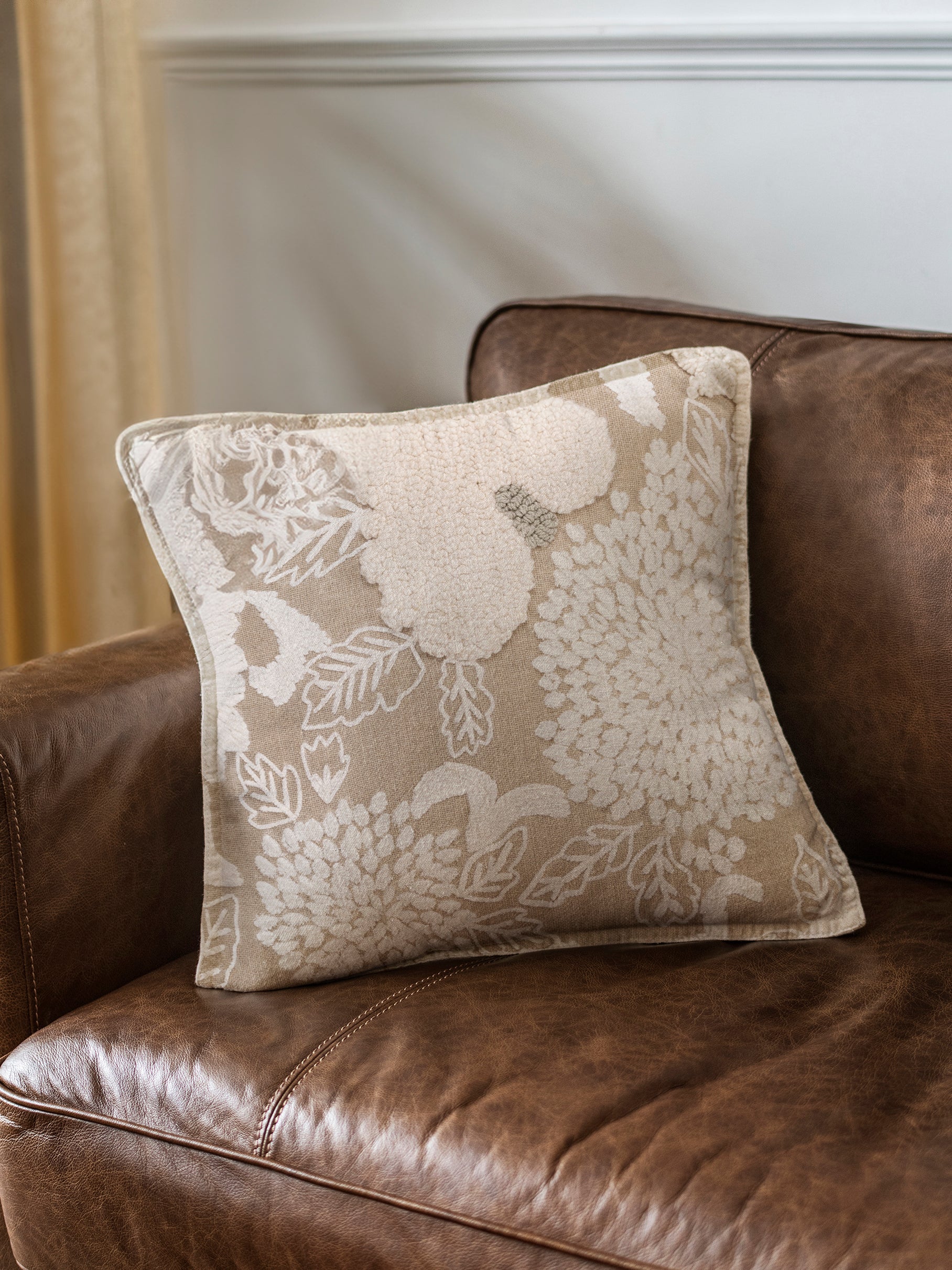 Natural cotton throw pillow 20″×20″ with tufted floral motifs and refined embroidery in earth‑toned palette — thoughtful artisan accent