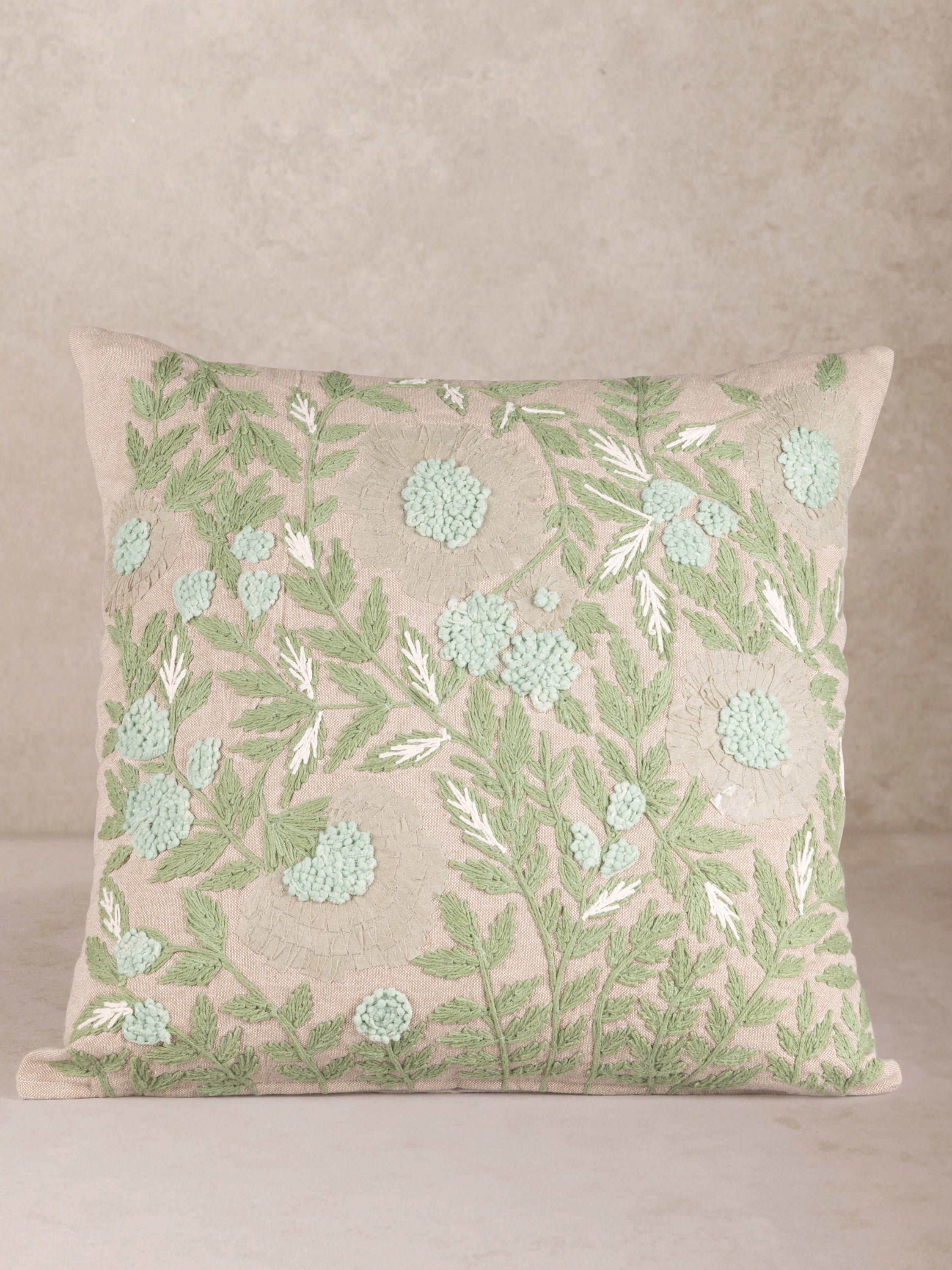 Handcrafted cotton throw pillow with botanical embroidery in soft greens and beiges — artisan luxury accent