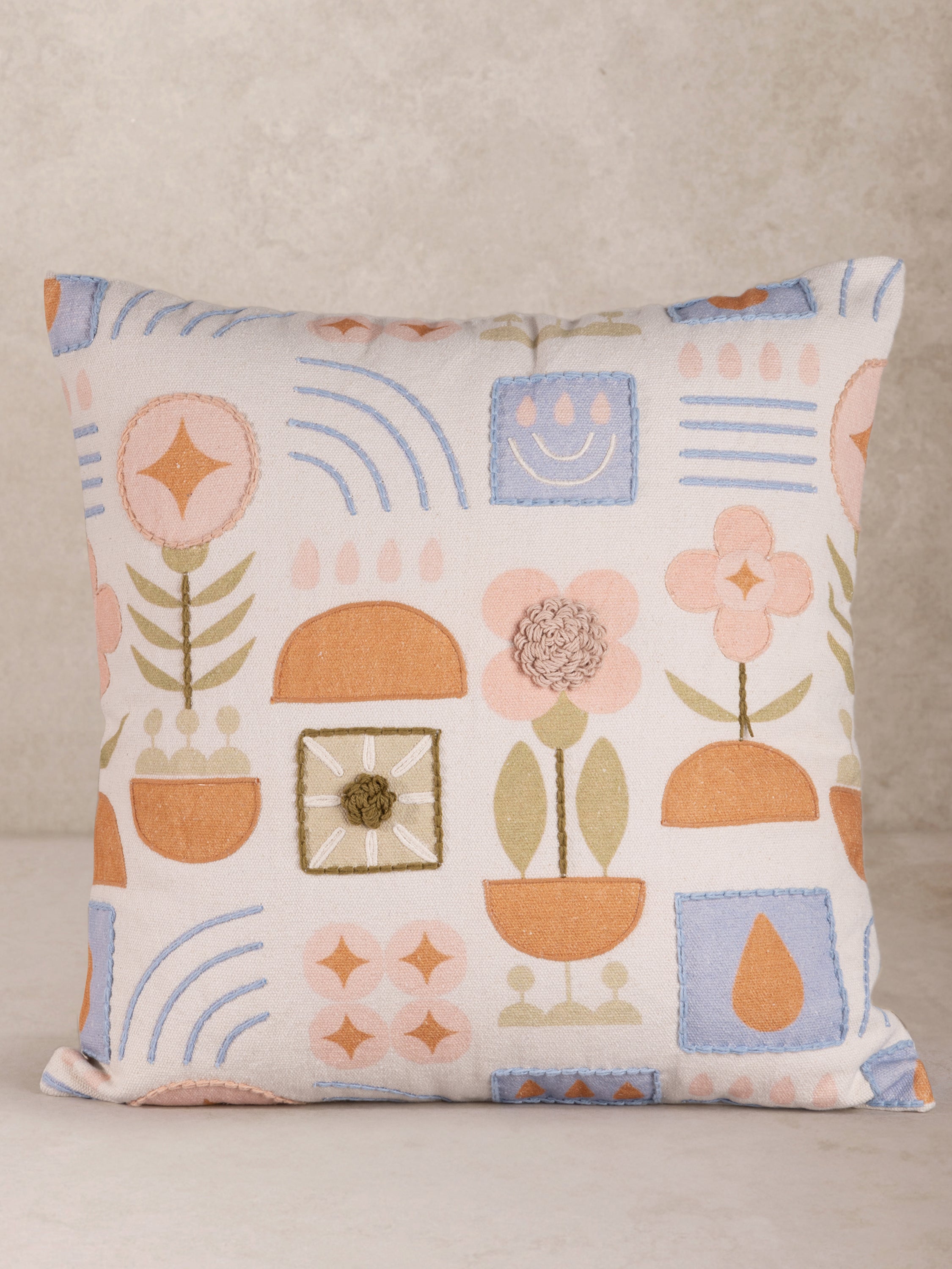 Hand-crafted cotton throw pillow with printed and embroidered motifs in pastel tones — artisan luxury accent