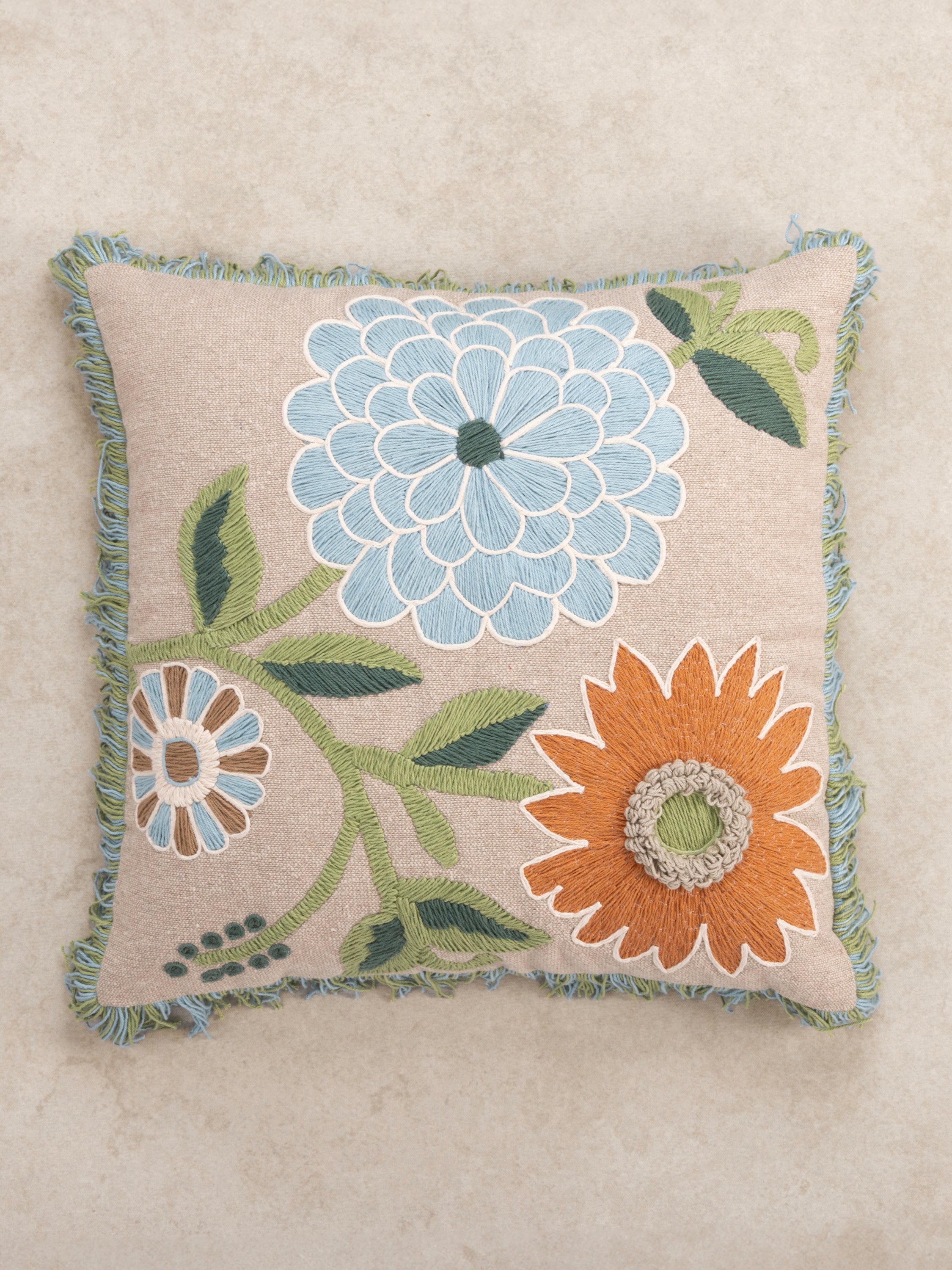 Textured floral pillow 20″×20″ in natural cotton with fringe edges and rich embroidered detail — refined decorative piece