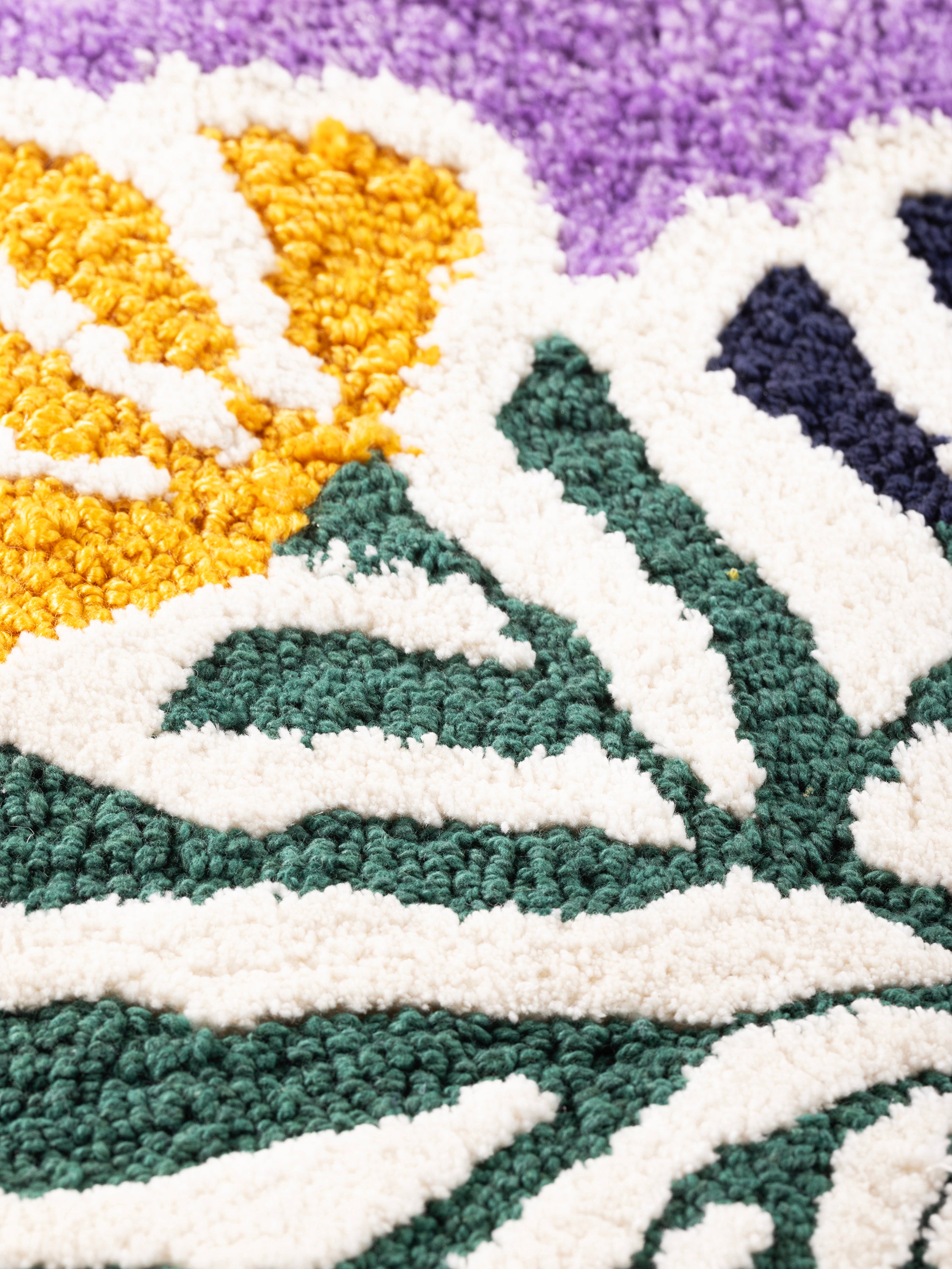 Close-up of hooked wool embroidery highlighting raised pile texture, defined floral shapes, and tonal variation across the lilac ground