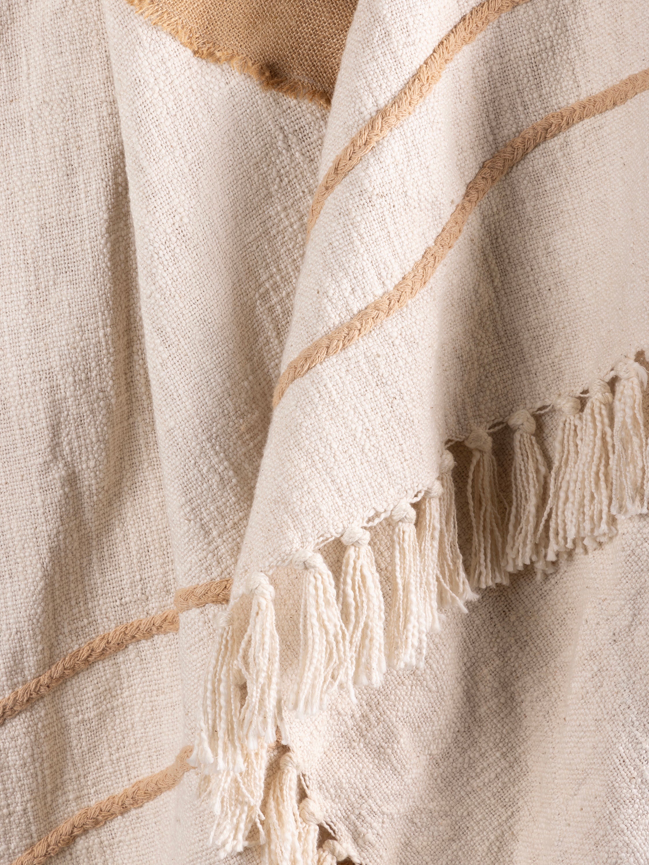 Soft natural cotton throw with embroidered pattern and tufted surface, draped on sofa — artisan-made comfort