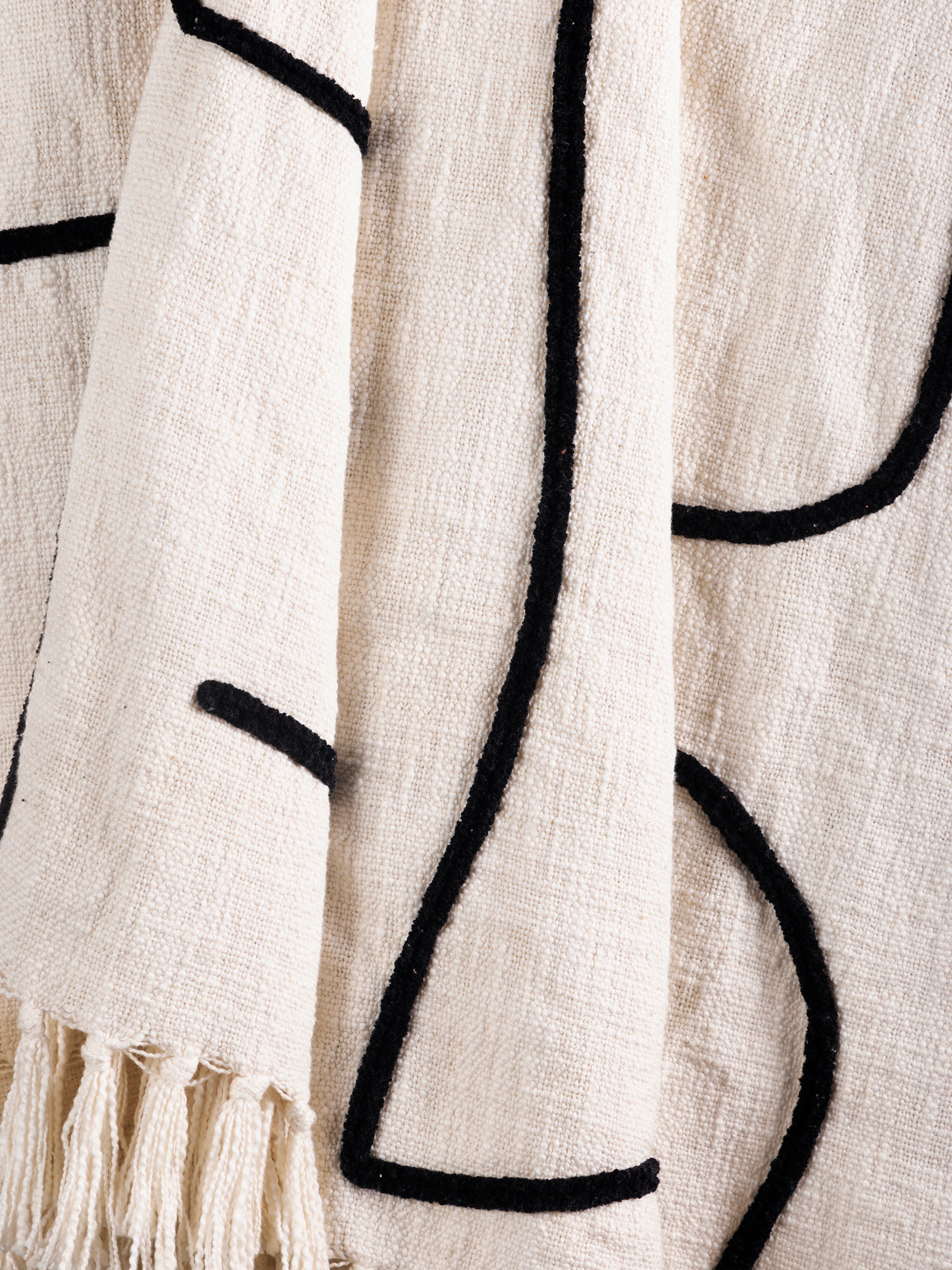 Close-up of the Slovenia throw showing the black linear pattern on the woven surface with fringe edge detailing.