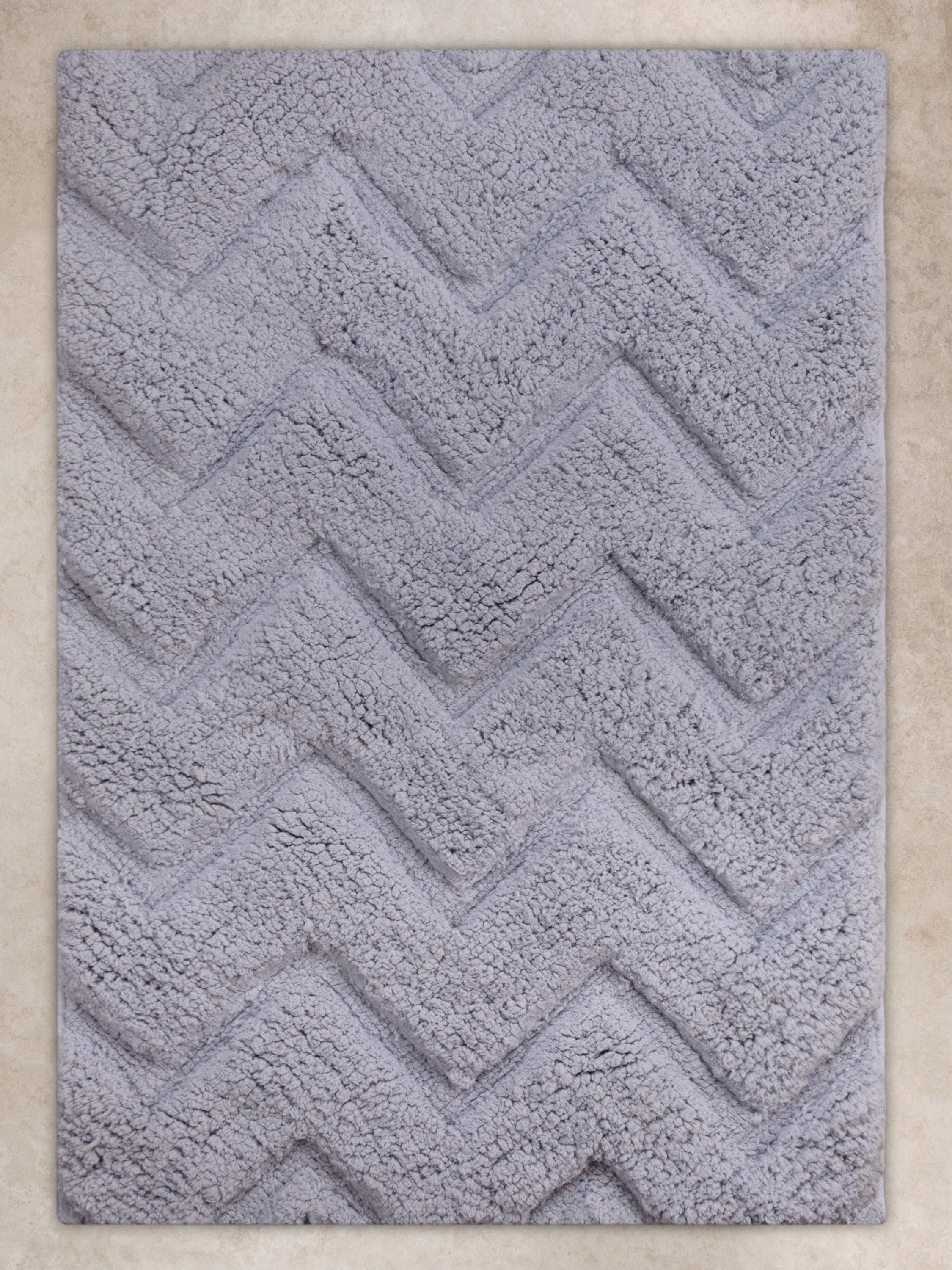 Gray microfiber bath mat with raised chevron pattern in tonal relief, front-facing view.