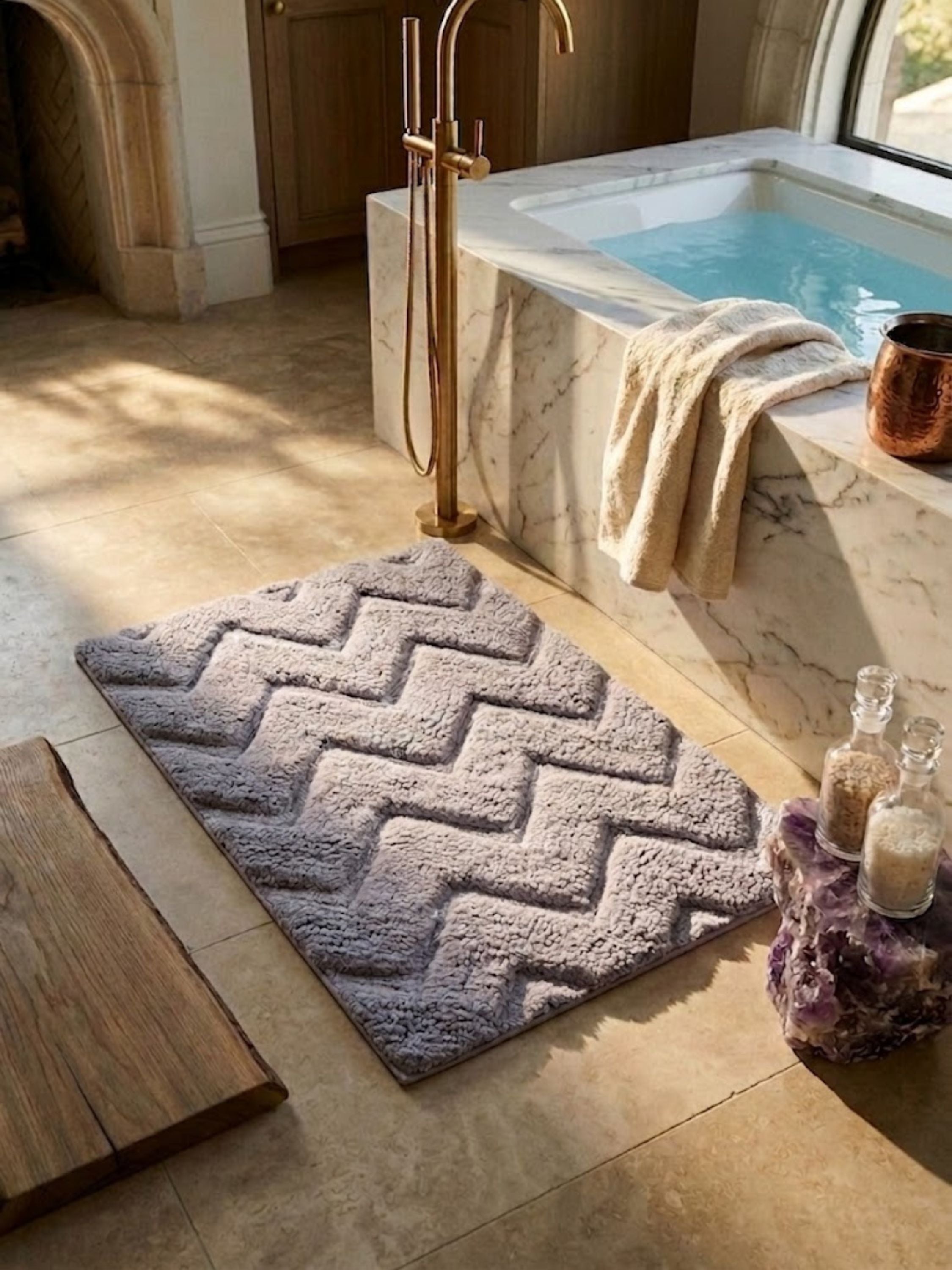 Gray microfiber chevron bath mat styled beside a marble soaking tub.