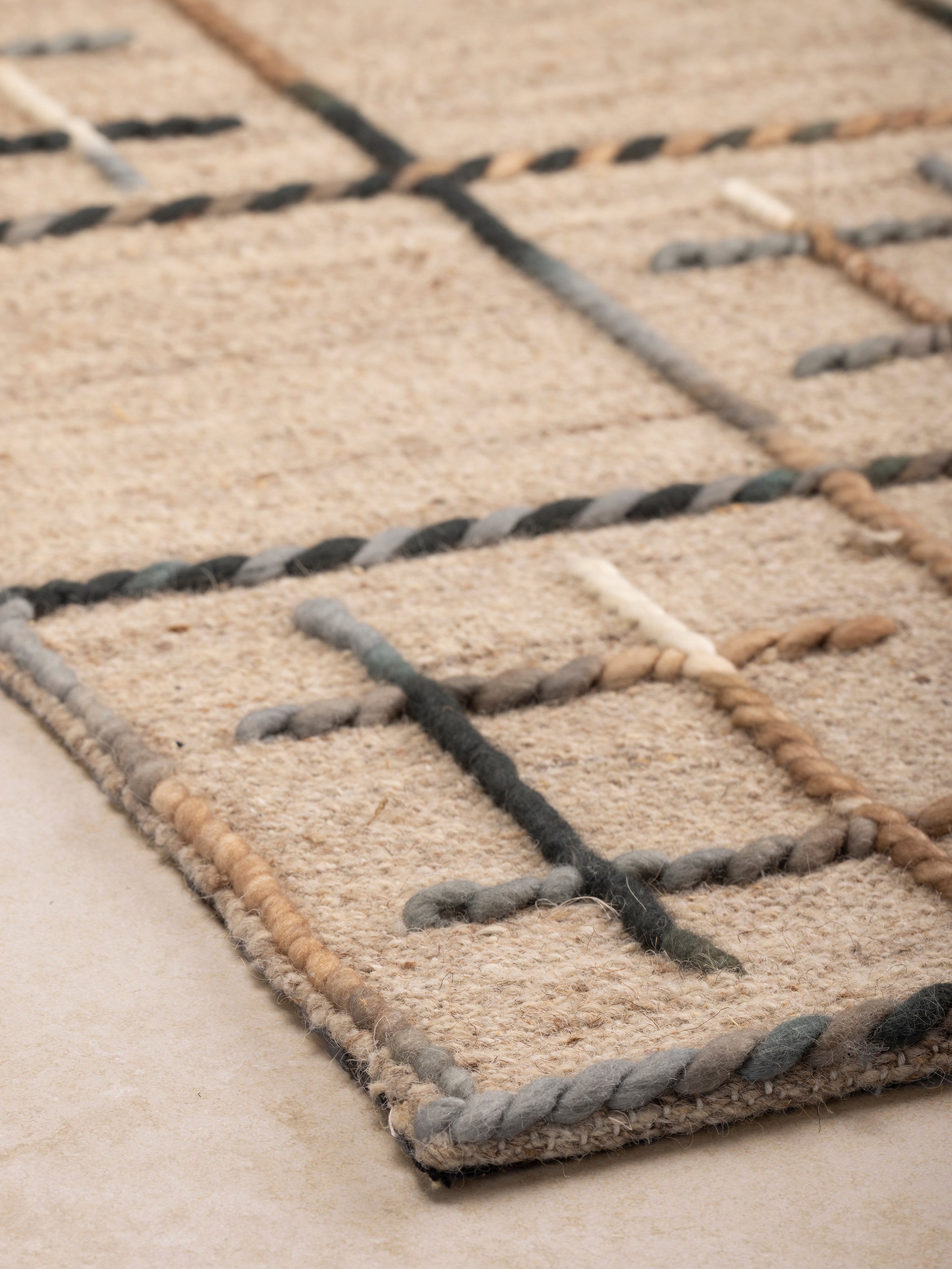 Artisanal beige and black area rug with subtle cross-stitch accents, ideal for living rooms and bedrooms