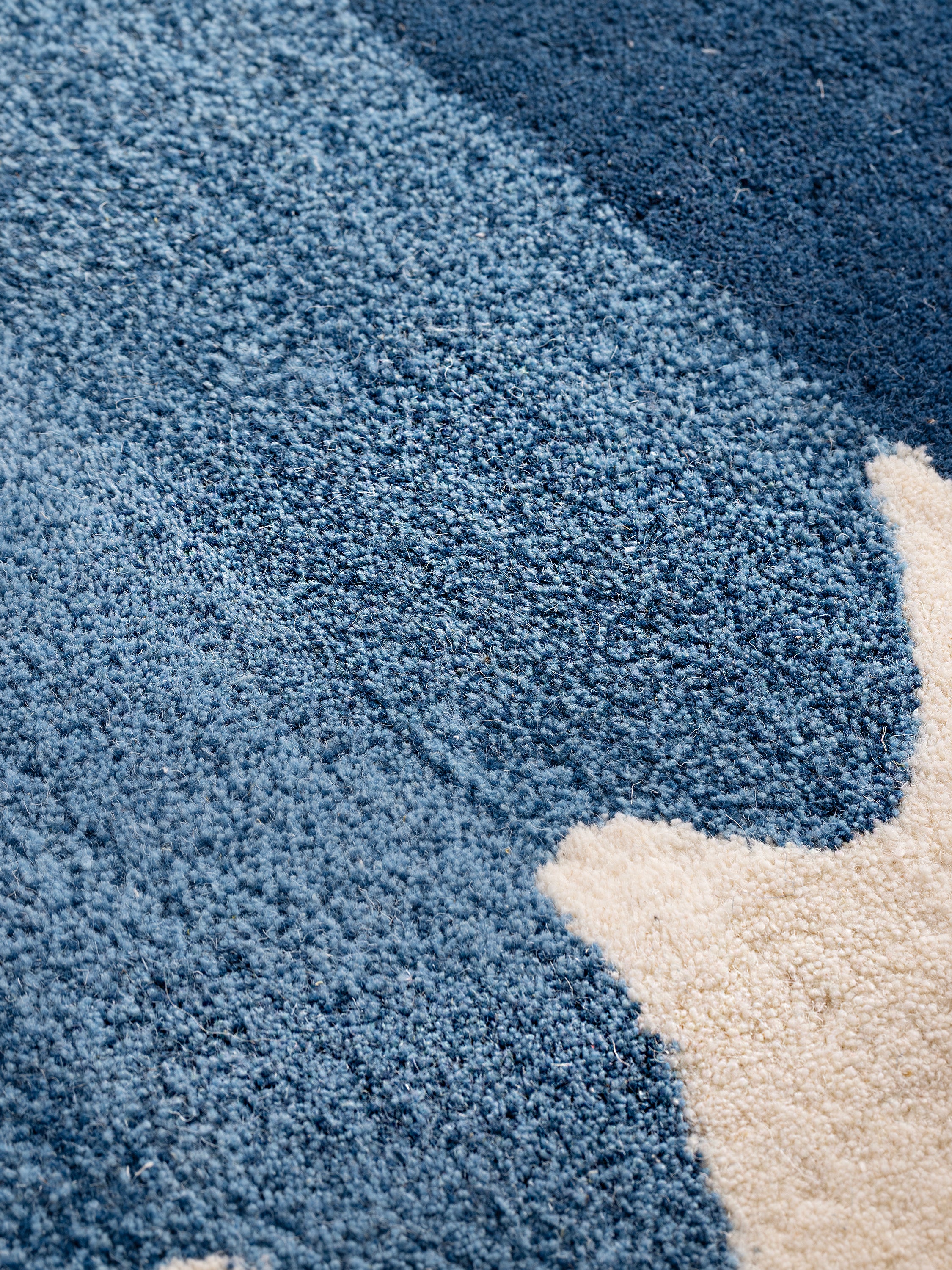 Close-up of Antigua rug medium pile texture in layered blue tones and soft ivory ground