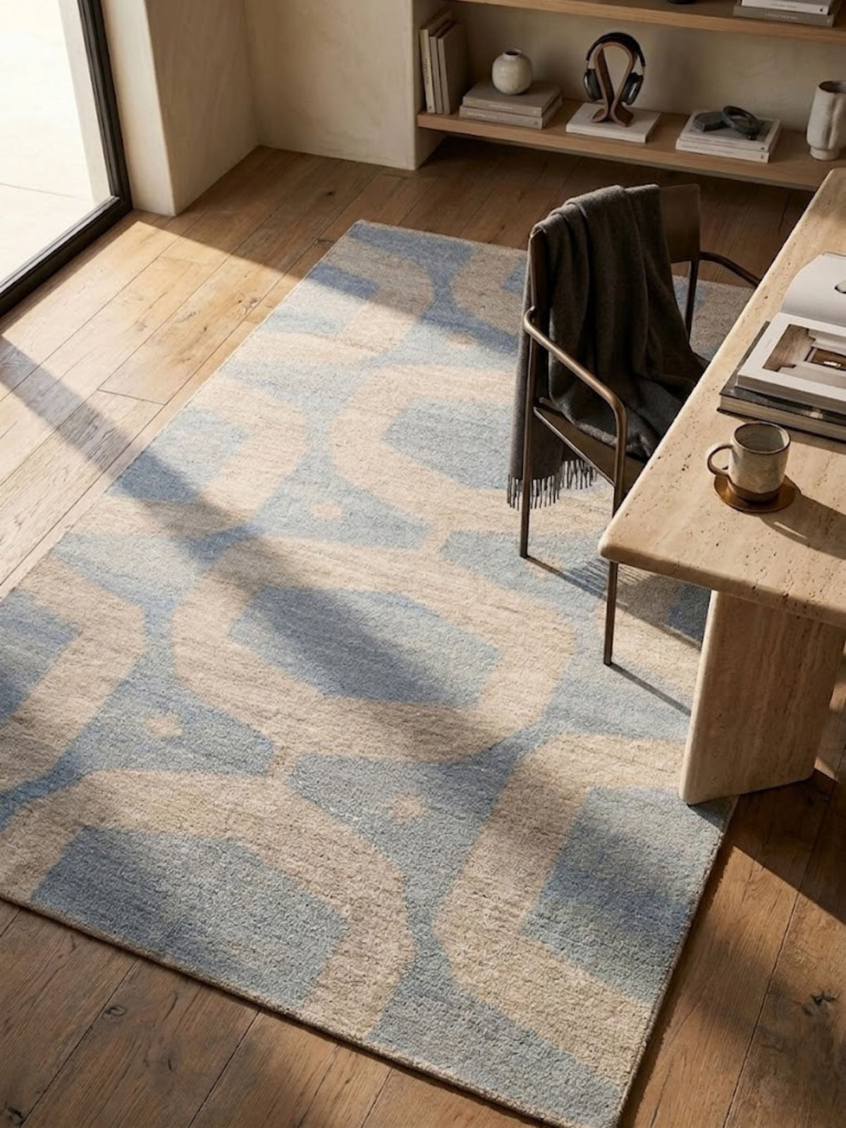 Flatwoven wool rug in blue and sand, partial pattern visible, styled on a wood floor.