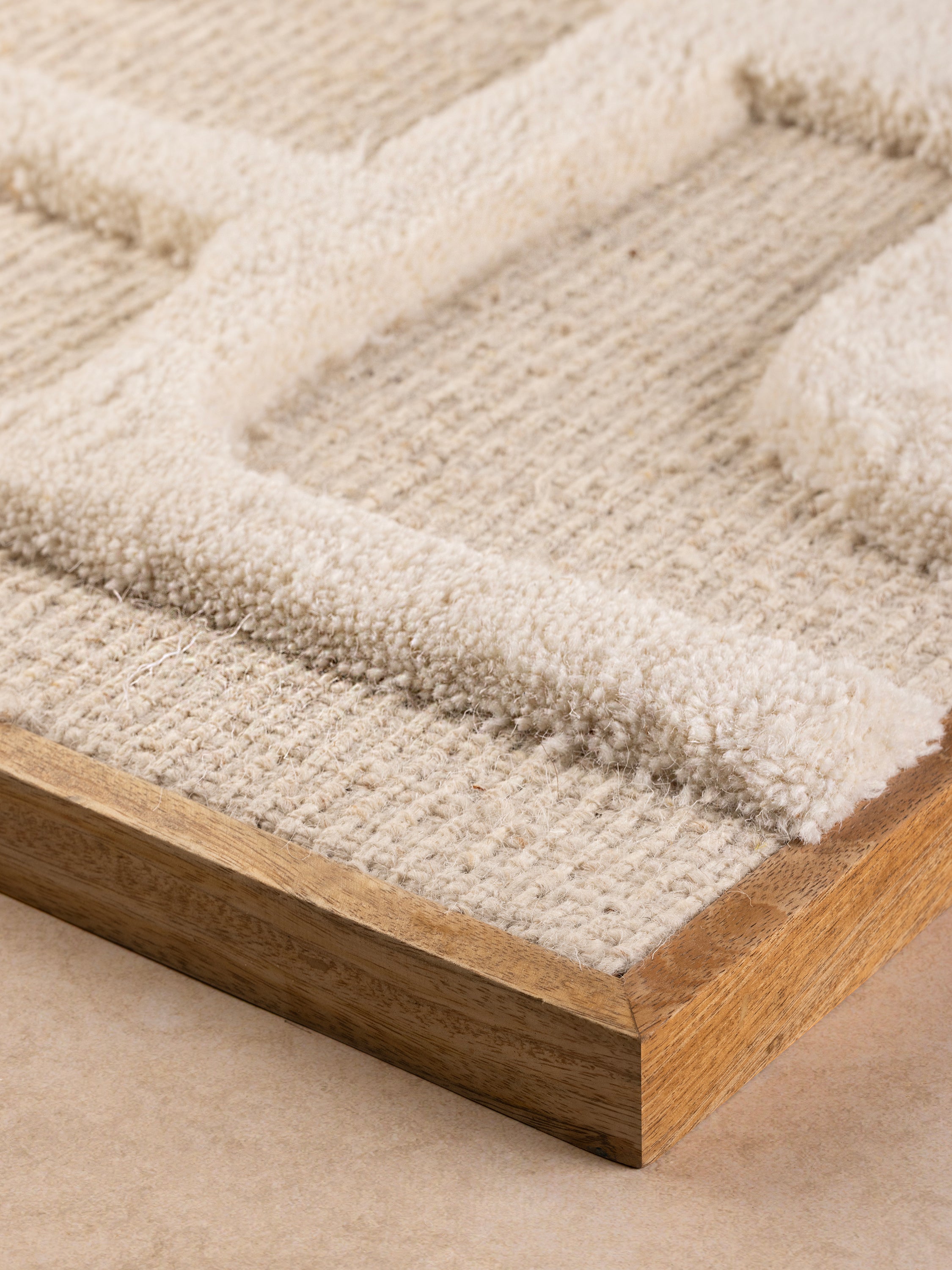 close-up of raised tufted geometric forms and natural wood frame