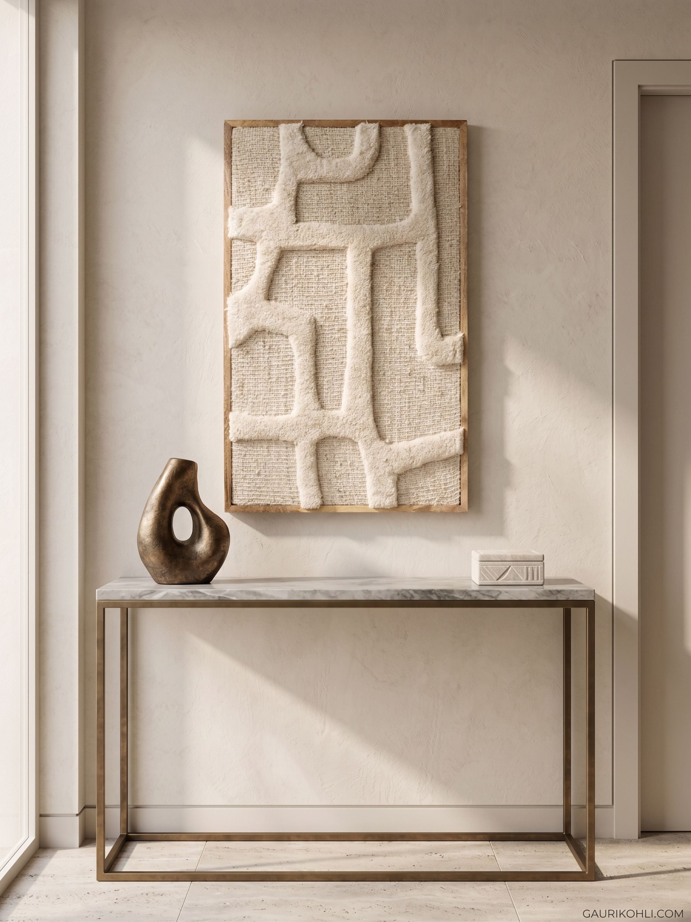 Textured tufted wool wall art in ivory tones with sculpted surface detail, styled above a metal console table in a minimal interior