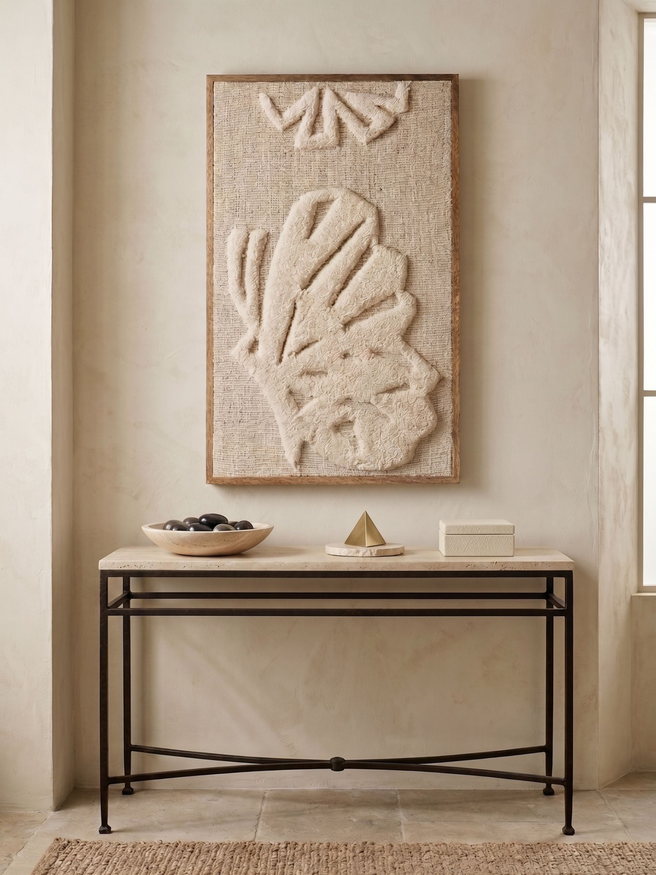 Tufted wool wall art with raised botanical motif in ivory tones, styled above a metal console table in a minimal neutral setting