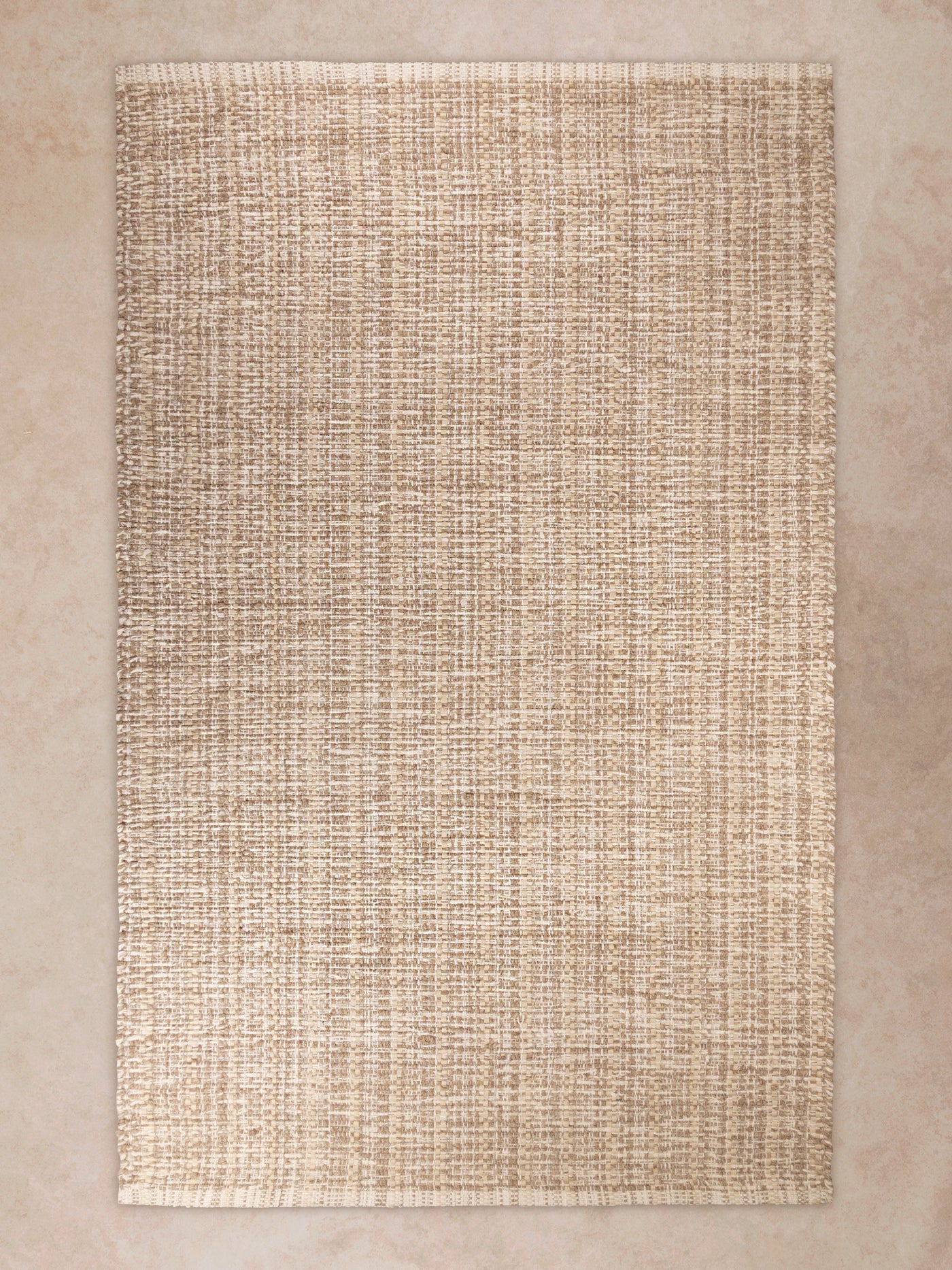 Handwoven area rug in natural beige tones shown in motion, with shifting light revealing dense woven texture, fine linear patterning, and subtle tonal variation