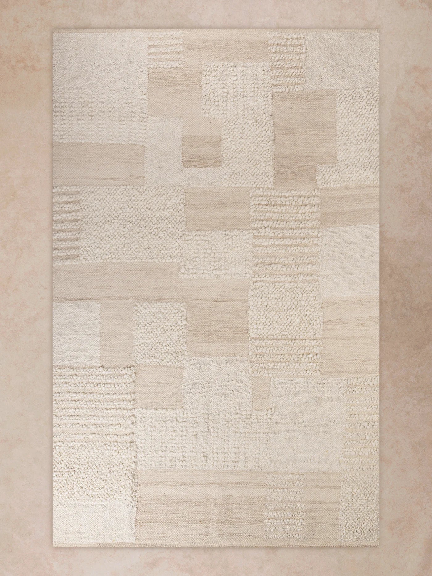 Handwoven area rug with subtle patchwork pattern in soft ivory tones shown in motion, with shifting light revealing nubby texture, tonal variation, and surface depth