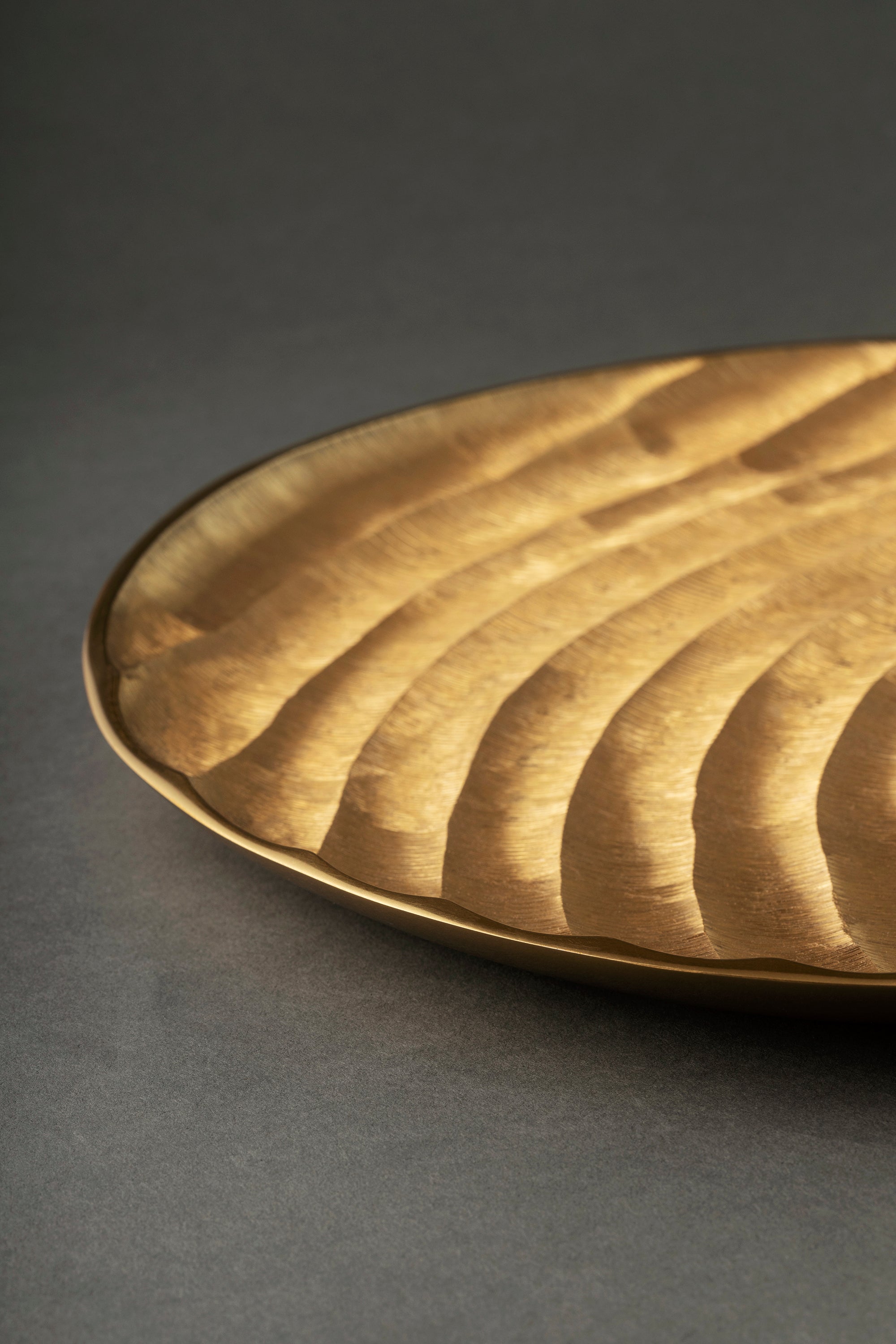 Artisan-made gold aluminum tray with subtle rib detail and luminous finish — luxury surface layer