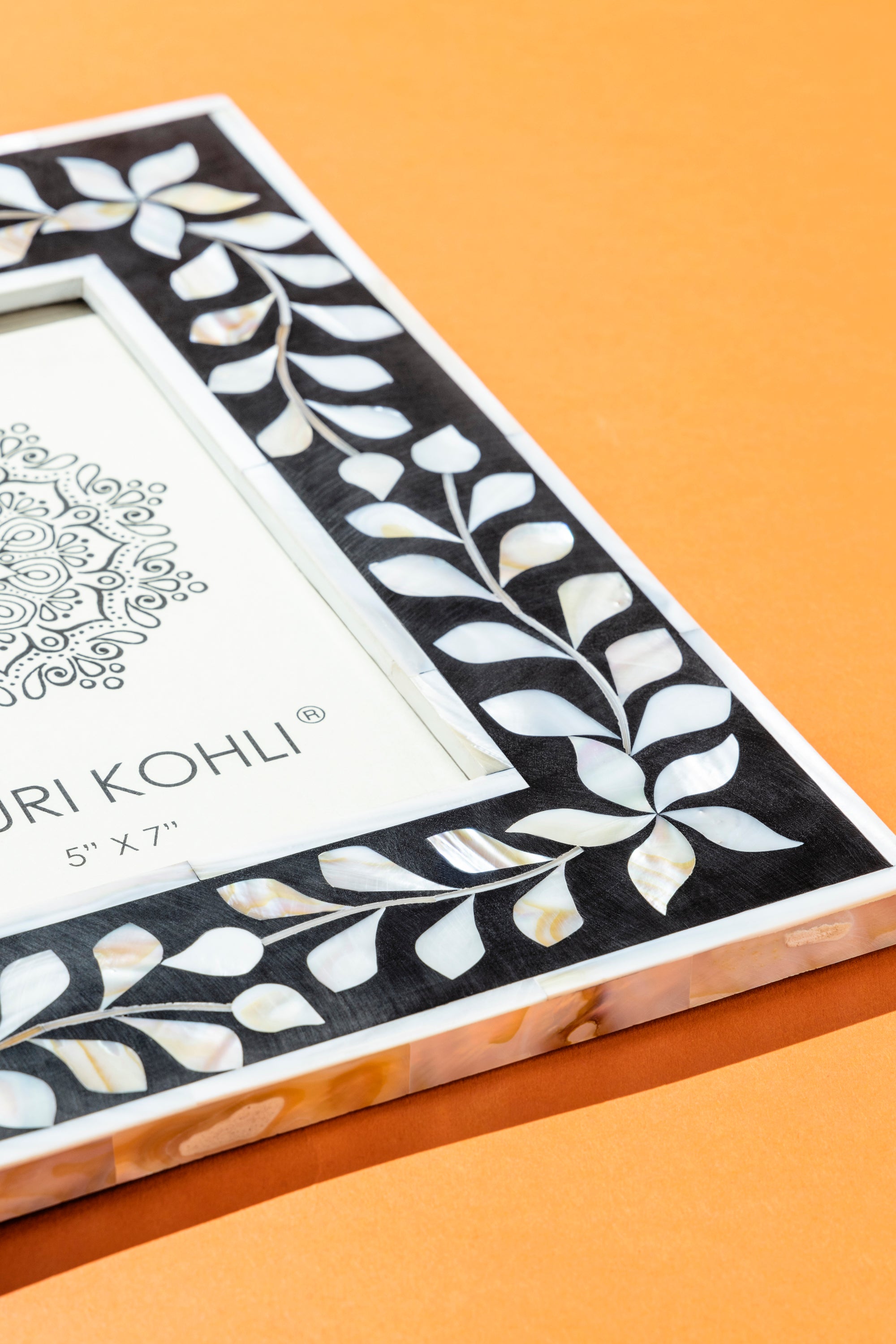 Artisan-made photo frame with luminous shell inlay and polished wood-resin border — luxury display layer