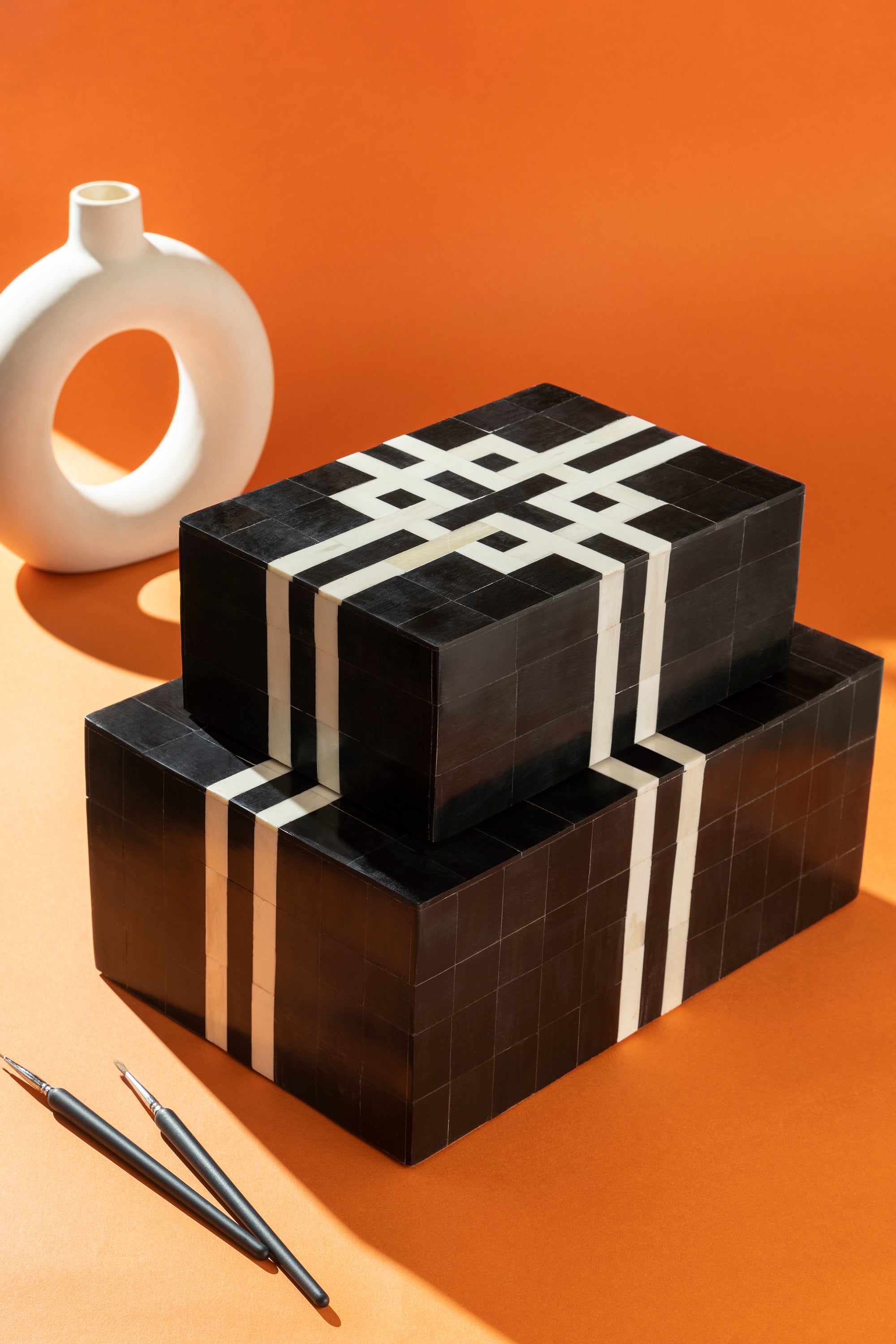 Artisan-made decorative boxes with black and ivory inlay detailing — luxury design layer