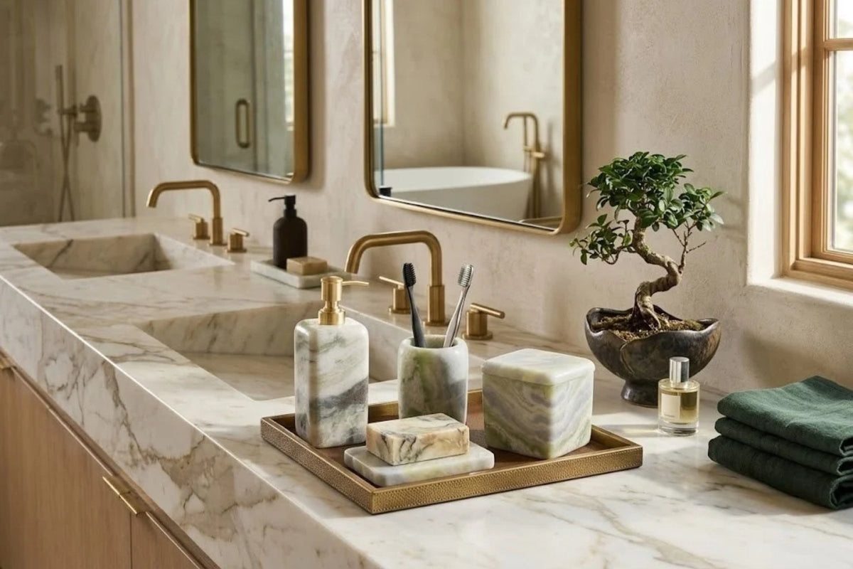 Green onyx dispenser, tumbler and canister grouped on a brass tray across a white marble double vanity