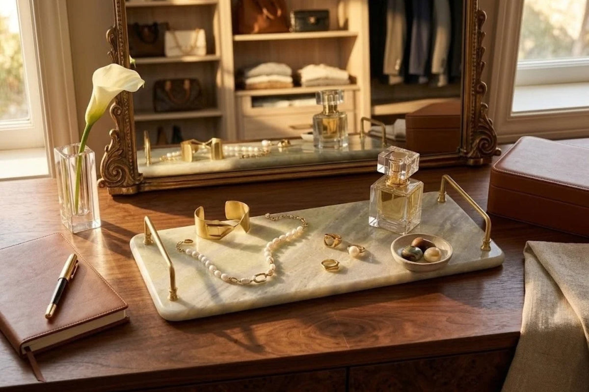 Cream onyx tray with brass handles holding pearls, rings and a perfume bottle on a walnut dressing table