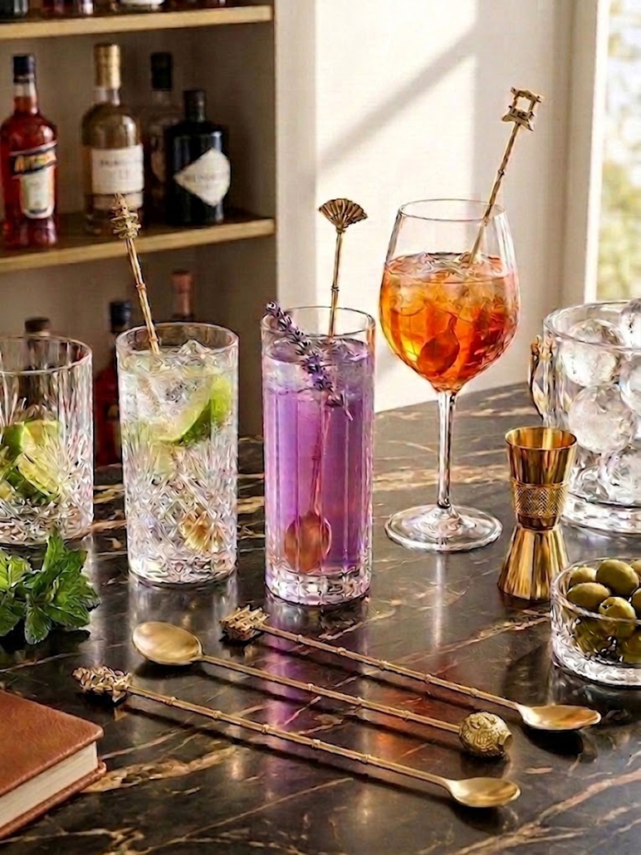 Magnolia gold cocktail stirrers styled with crystal glassware and artisan cocktails, bringing a refined decorative accent to home bar and entertaining settings.