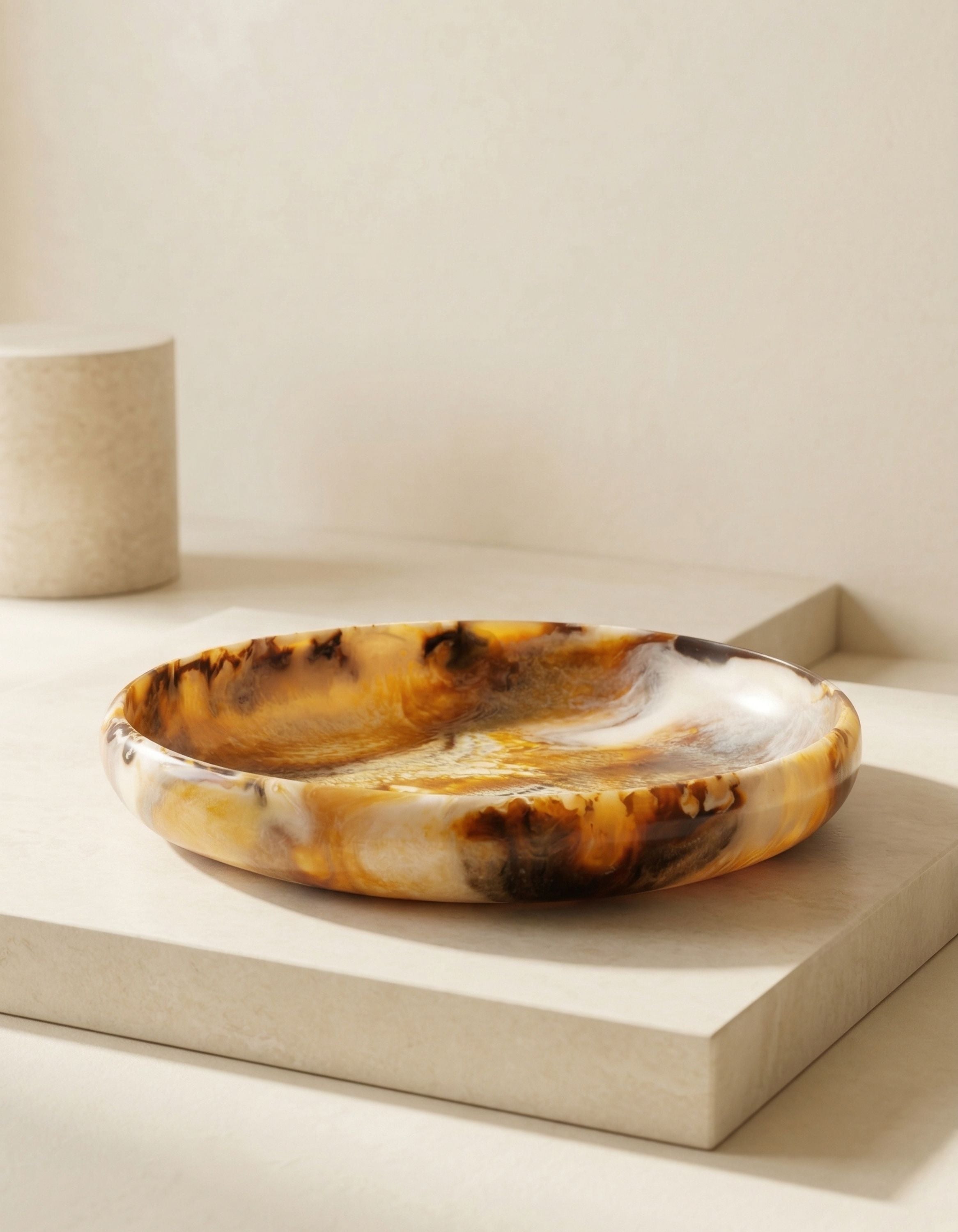 Amber swirl resin decorative bowl displayed on a neutral pedestal surface highlighting its organic form and marbled finish