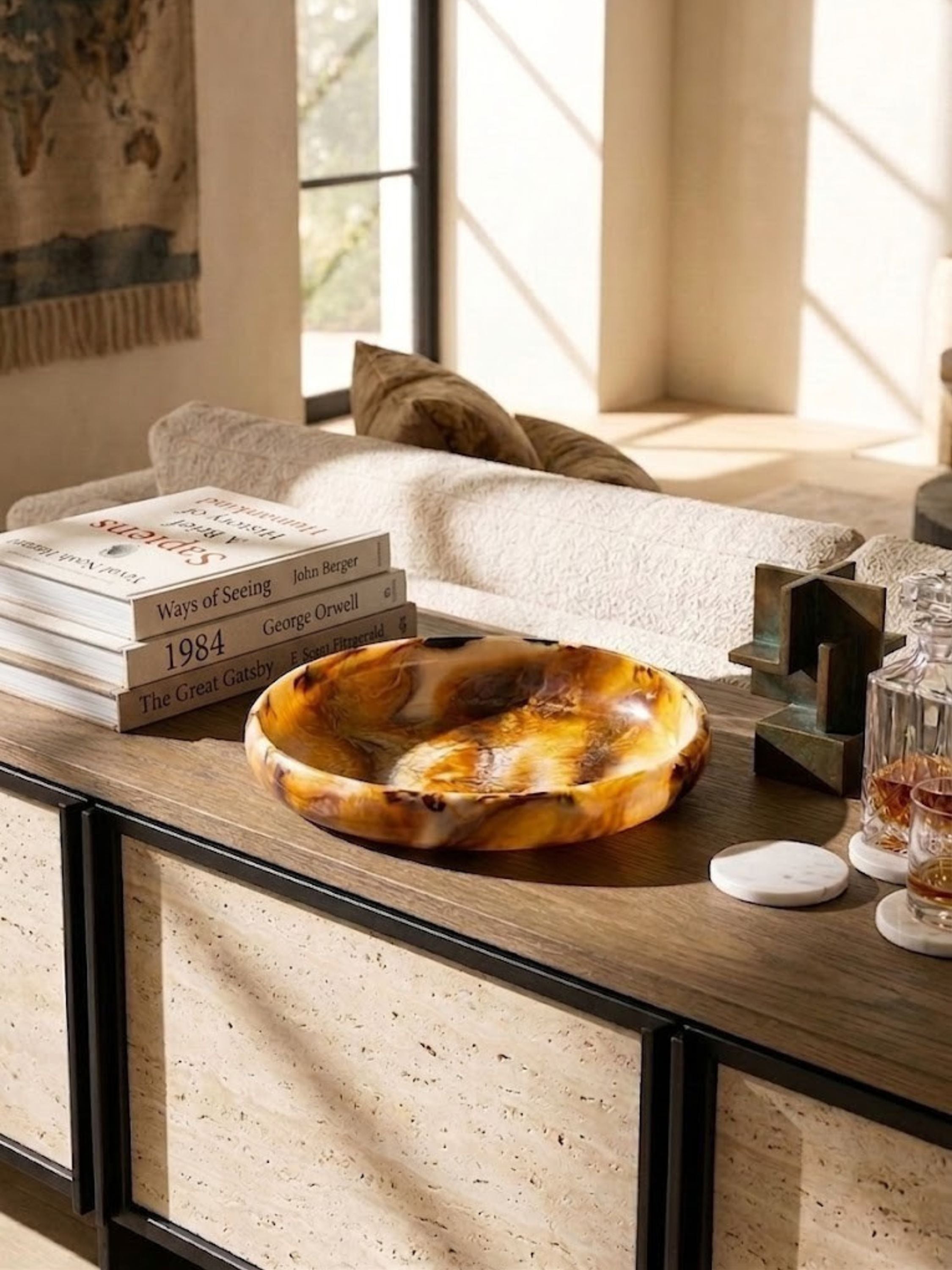 Amber and ivory marbled resin bowl on a console table, swirling color pattern across the rim.