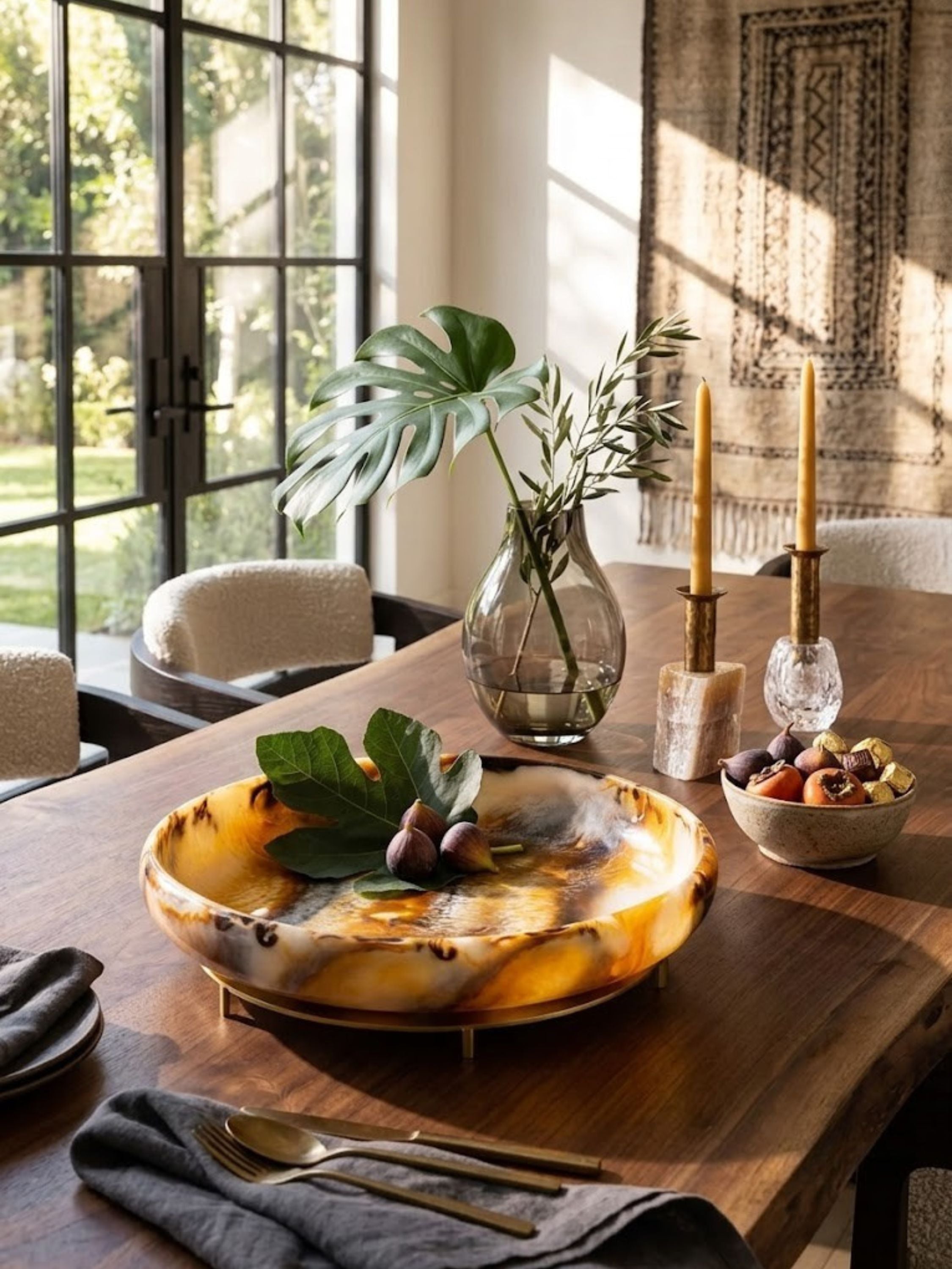 Marbled resin bowl with a raised base, amber and ivory tones, set on a dining table.
