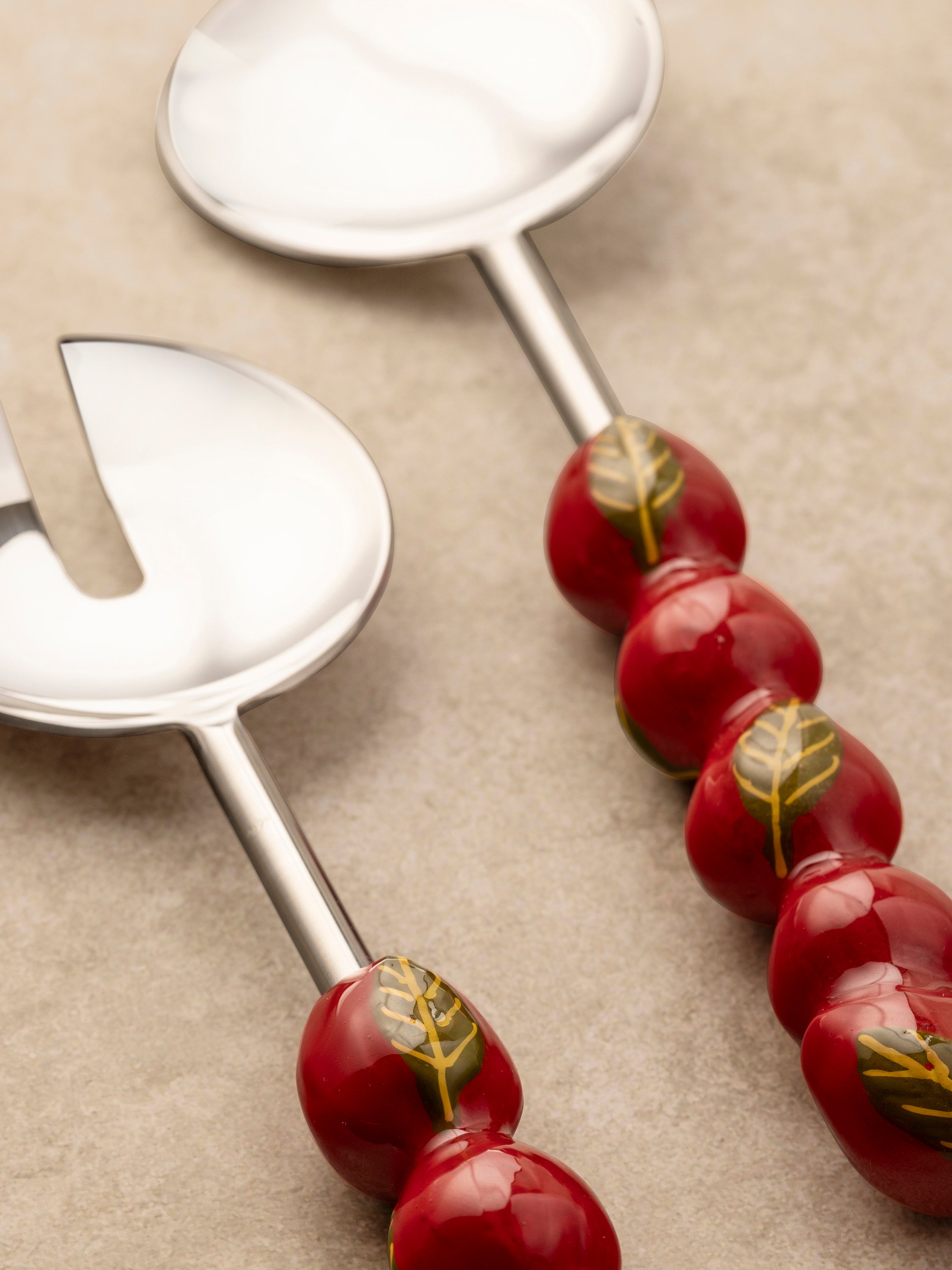 Close-up of the Very Berry salad server handle showing hand-applied enamel botanical detailing and smooth polished surface.