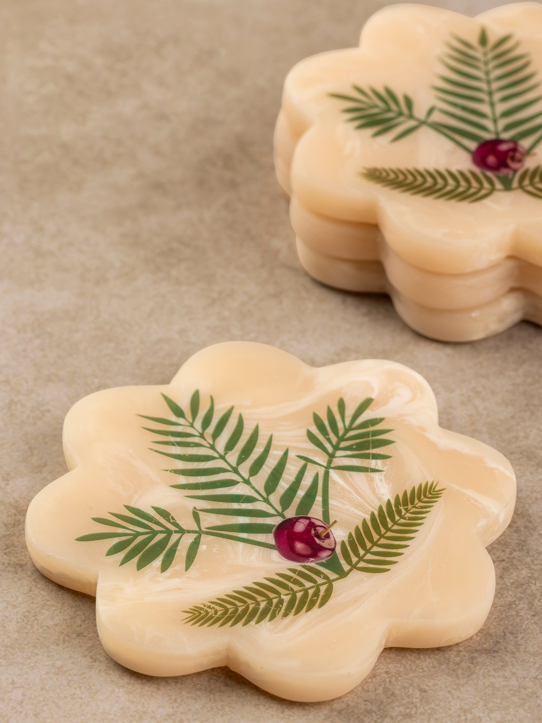 Close-up of single scalloped resin coaster showing botanical print, smooth surface finish, and softly scalloped edge