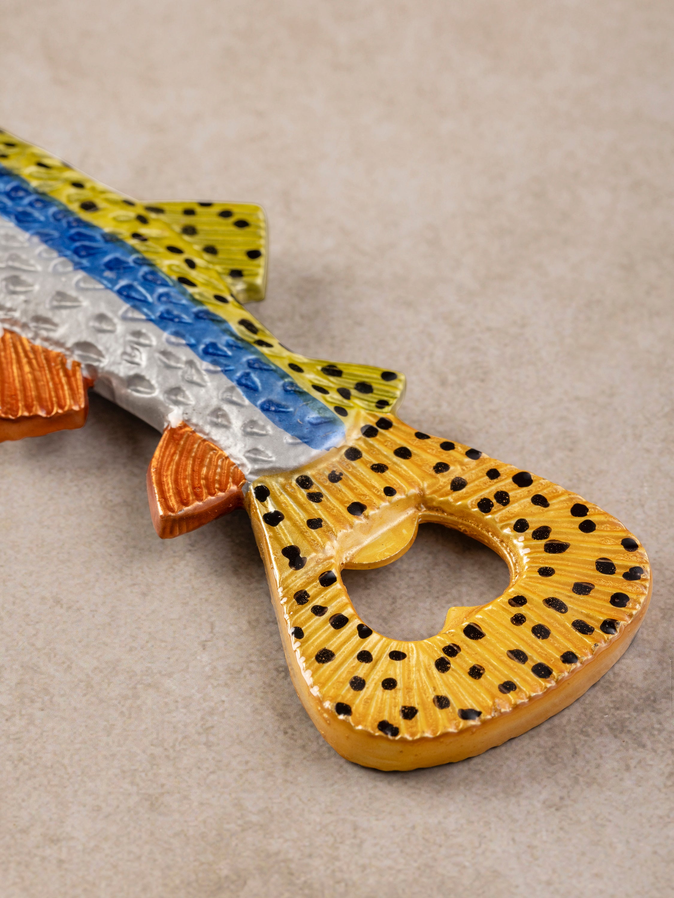 Close-up of fish bottle opener showing textured tail detail and integrated opener head with polished surface