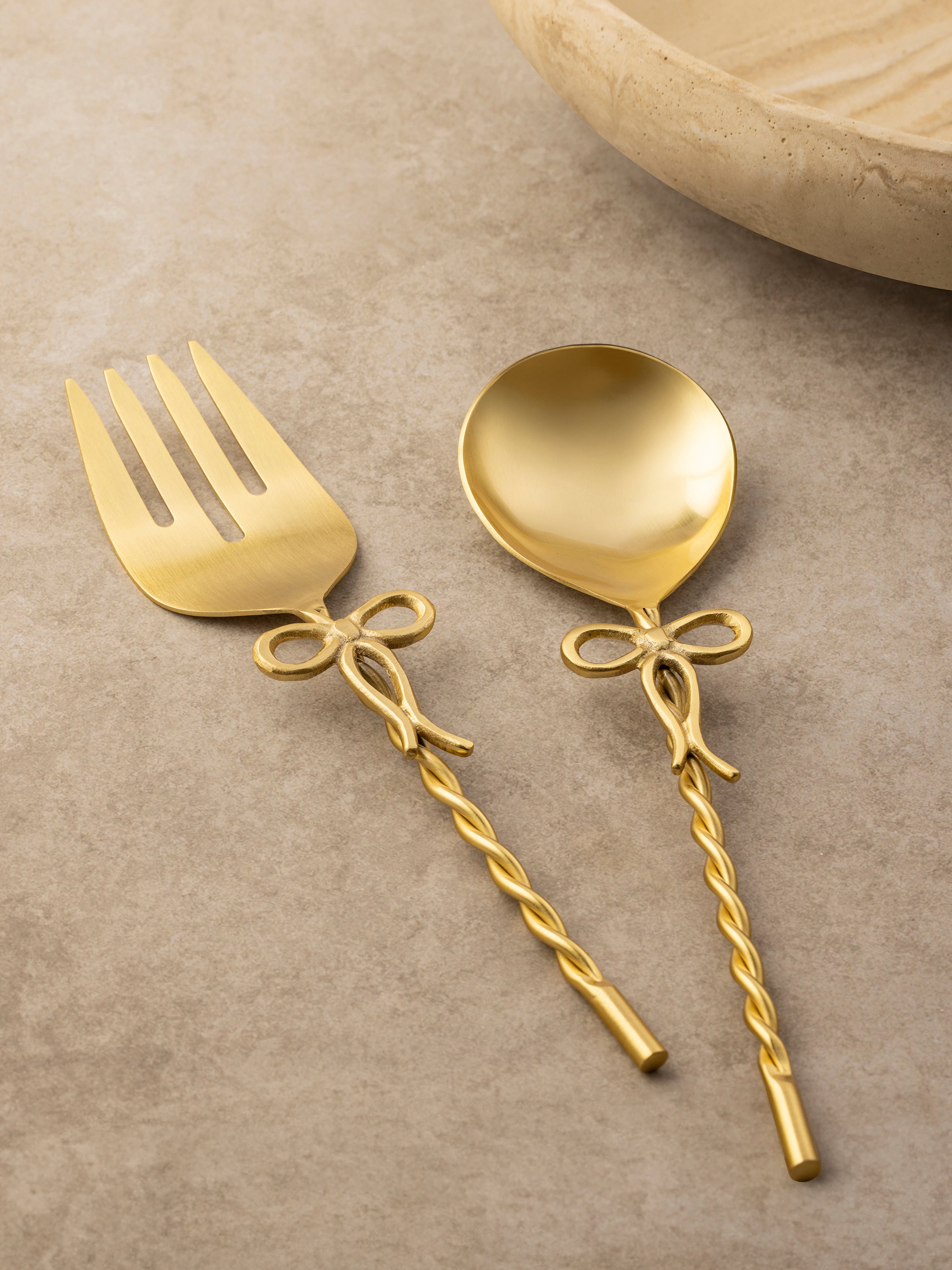Imperial salad server pair with sculpted bow-form handles arranged in a flat-lay composition.