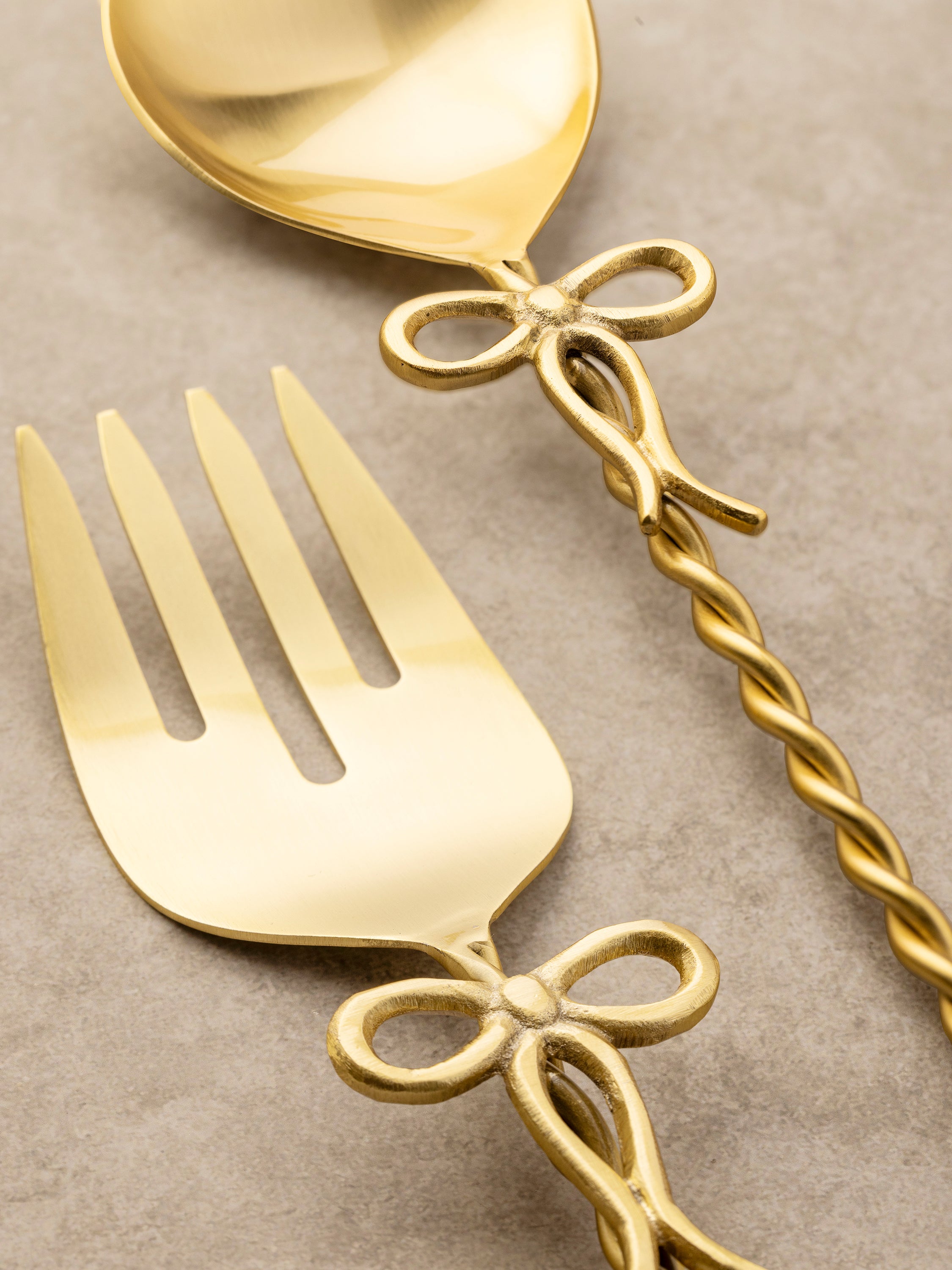 Close-up of an Imperial salad server's twisted brass handle, showing its spiral form and polished surface.