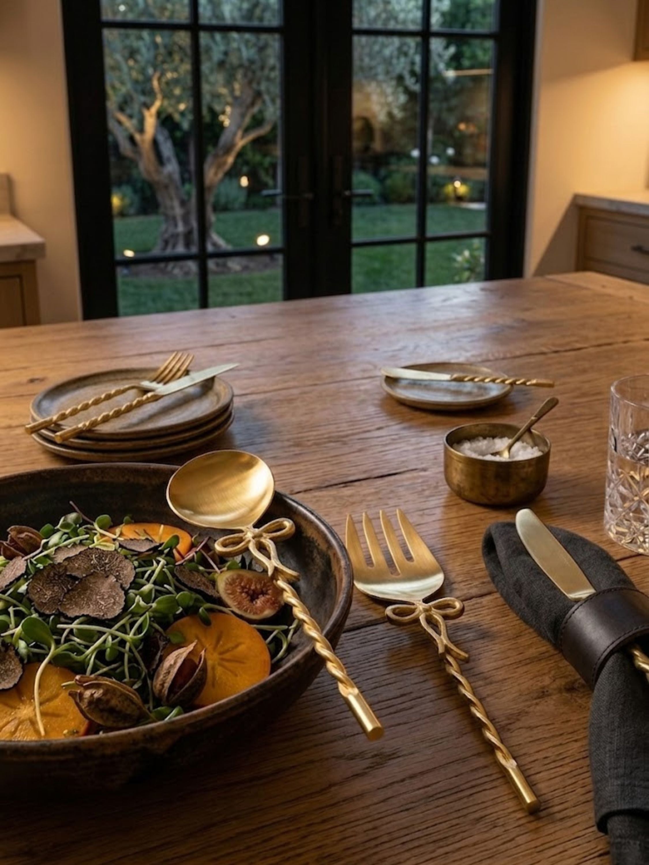 Imperial gold salad servers presented on a set dining table, their twisted gold handles beside a seasonal salad.