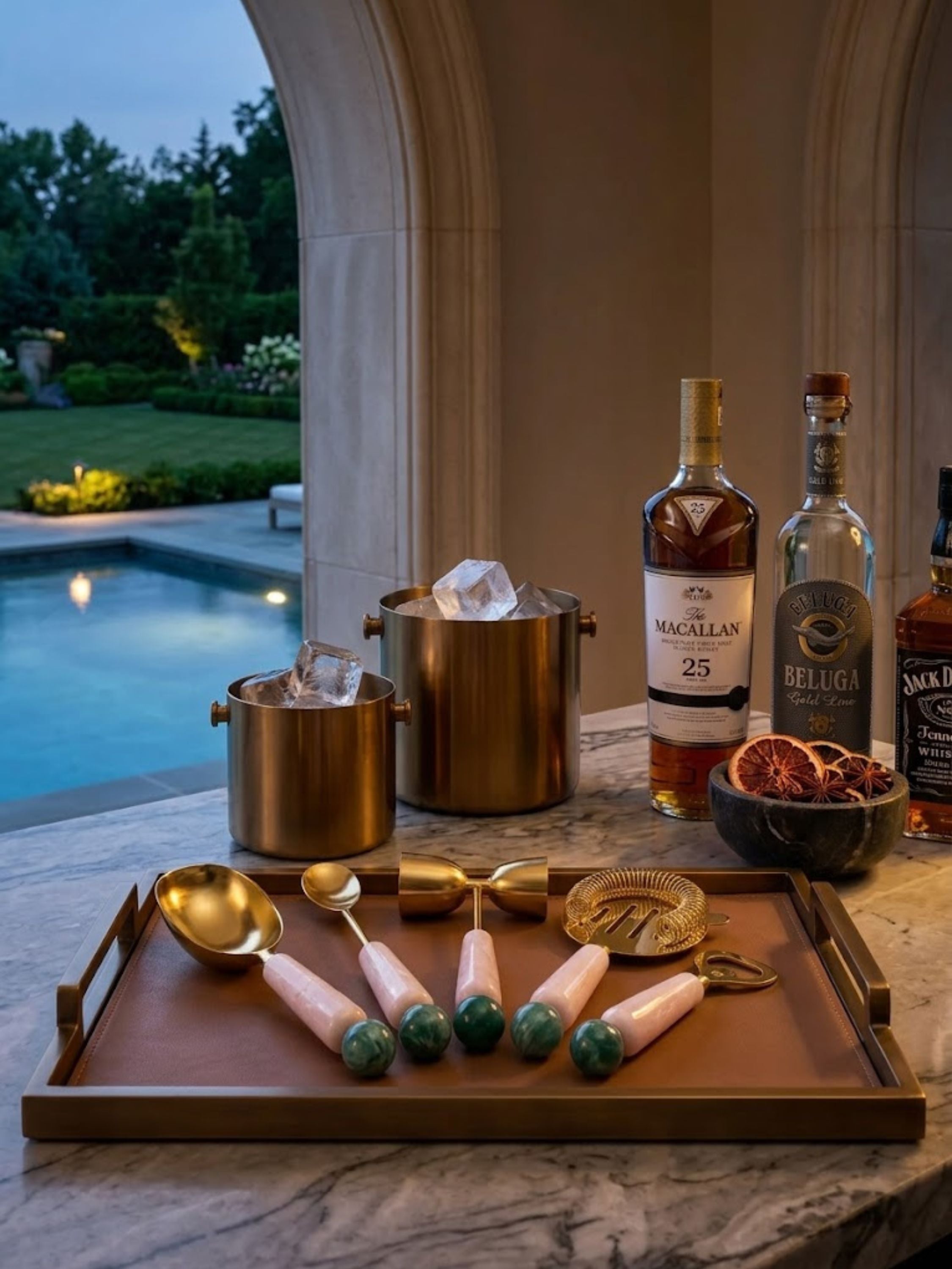 Copenhagen resin bar tools arranged on a serving tray beside premium spirits and ice buckets, creating a refined poolside cocktail station for evening entertaining.