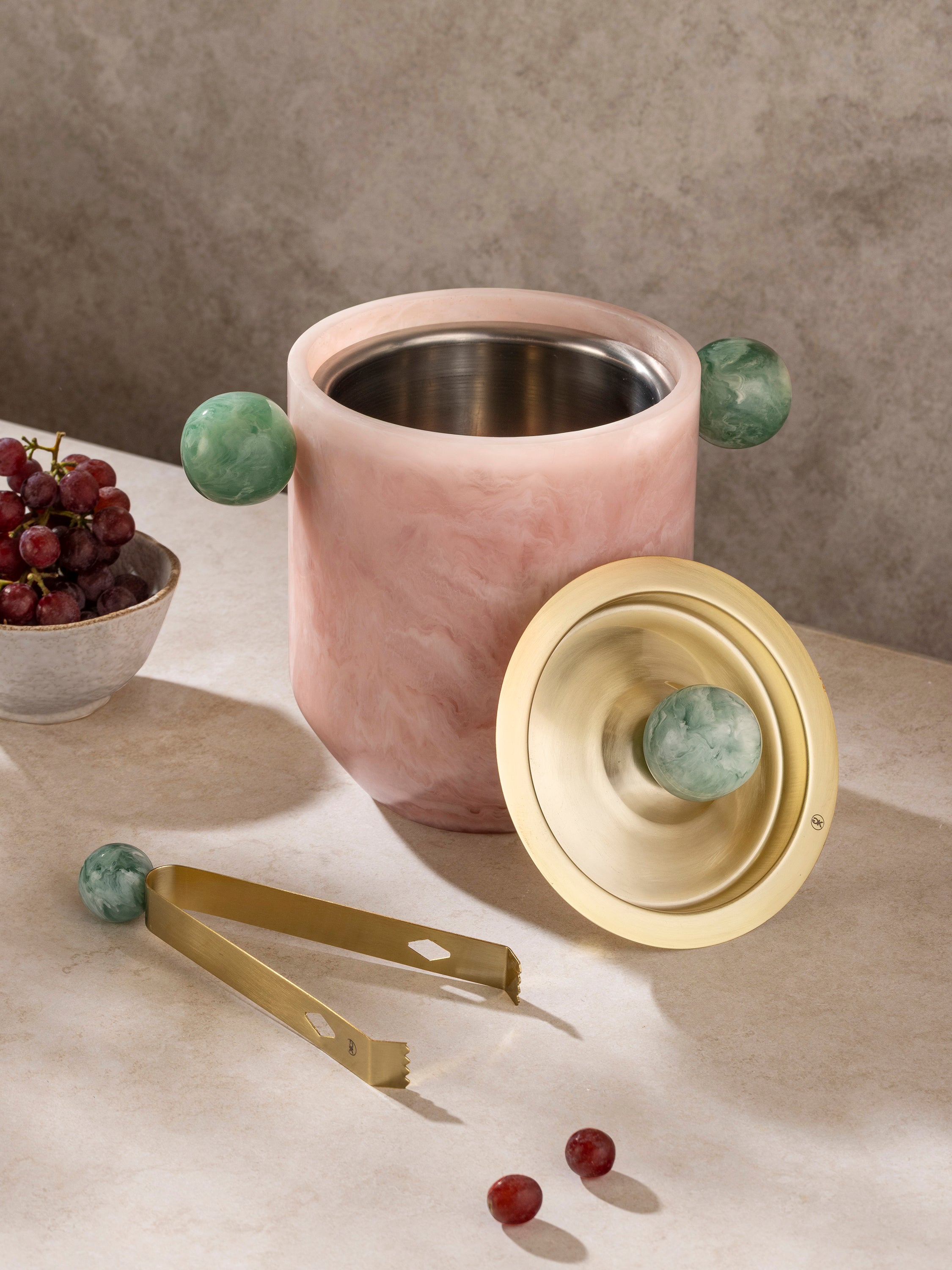 Marbled resin ice bucket with brass lid and tongs shown in a clean front-facing composition
