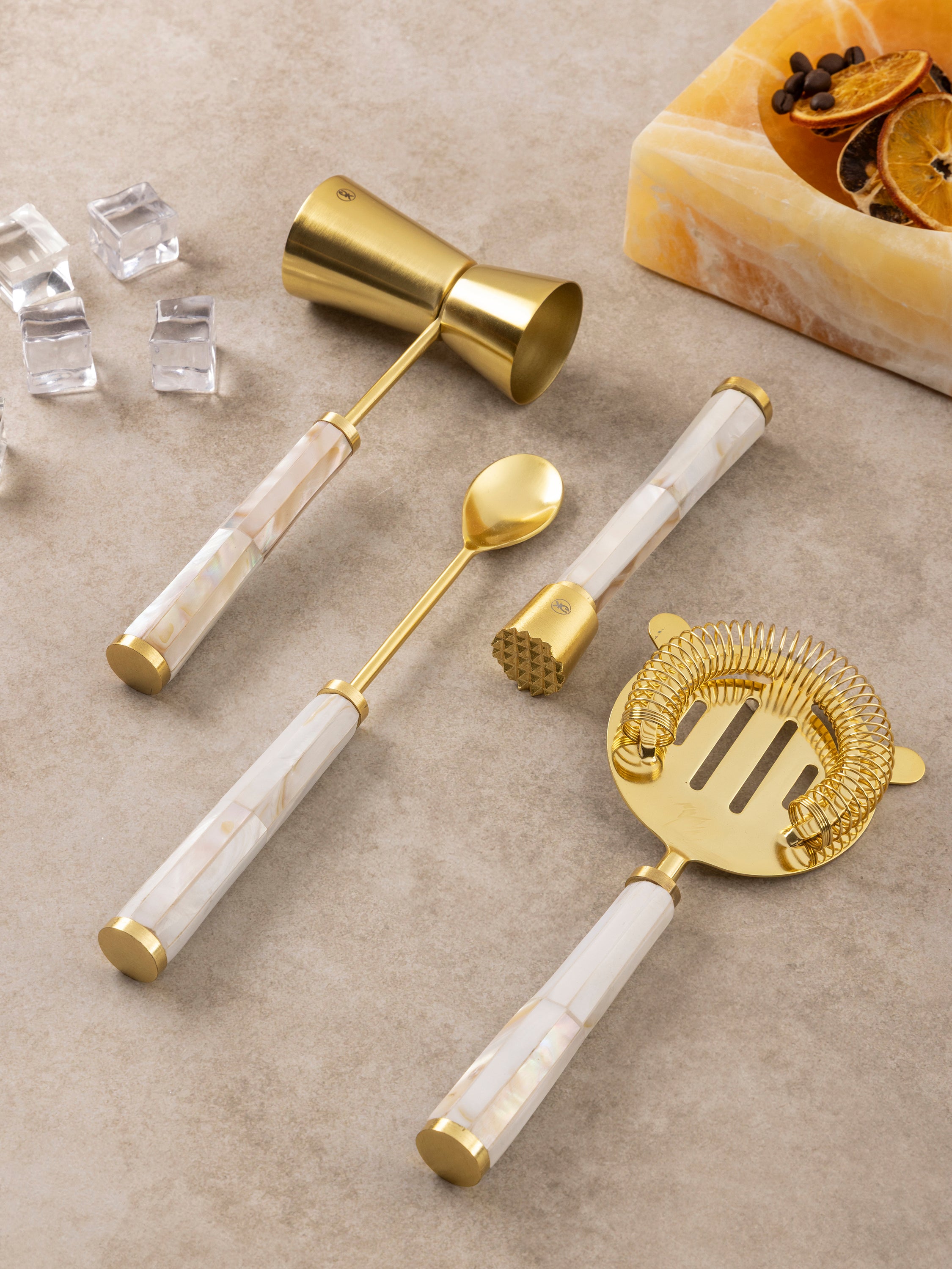 Darzi bar tools arranged together showing jigger, strainer, bar spoon, and opener with mother of pearl handle detailing