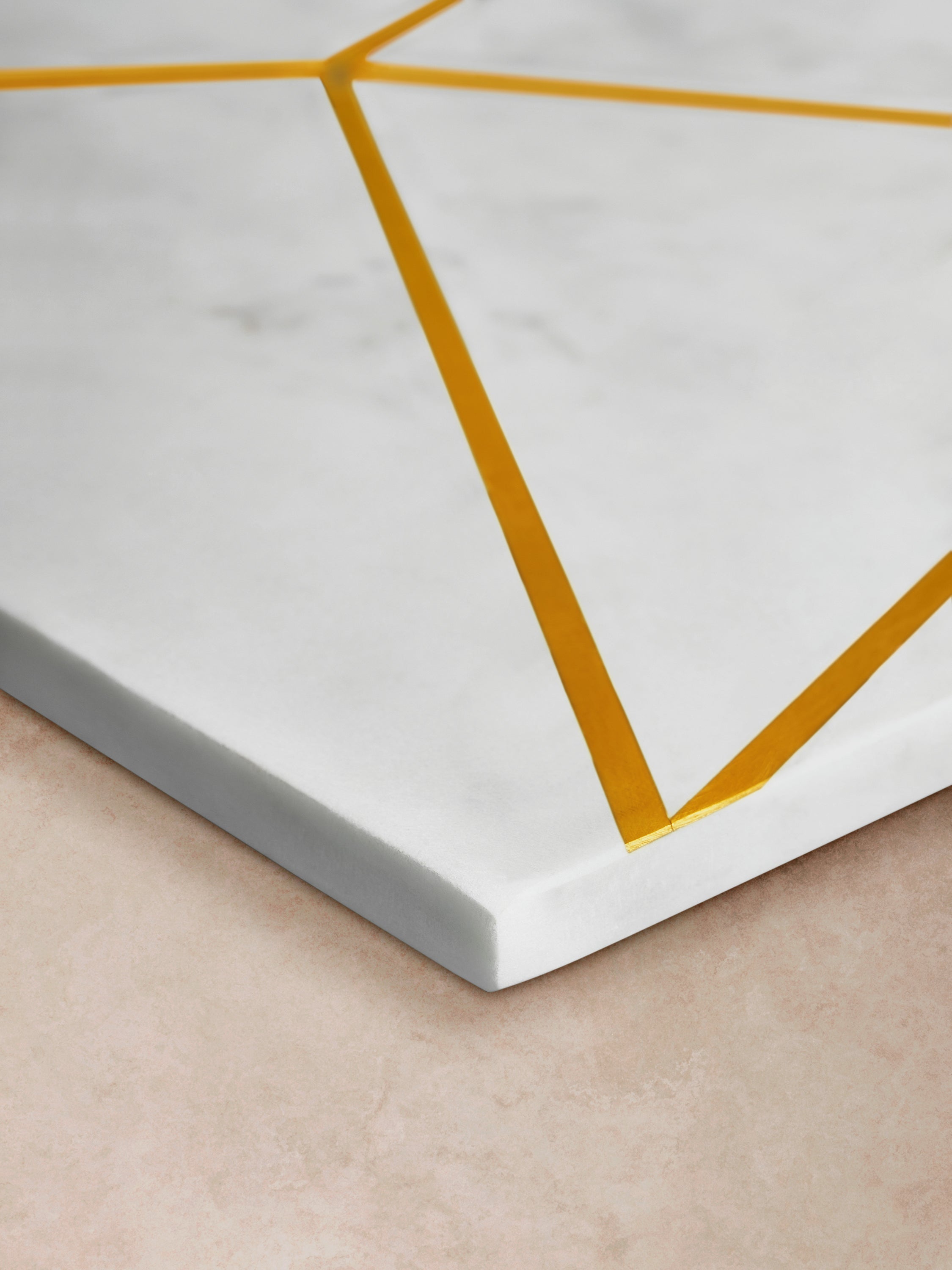 Close-up of marble board showing engraved brass lines, smooth polished finish, and crisp edge profile with subtle natural veining