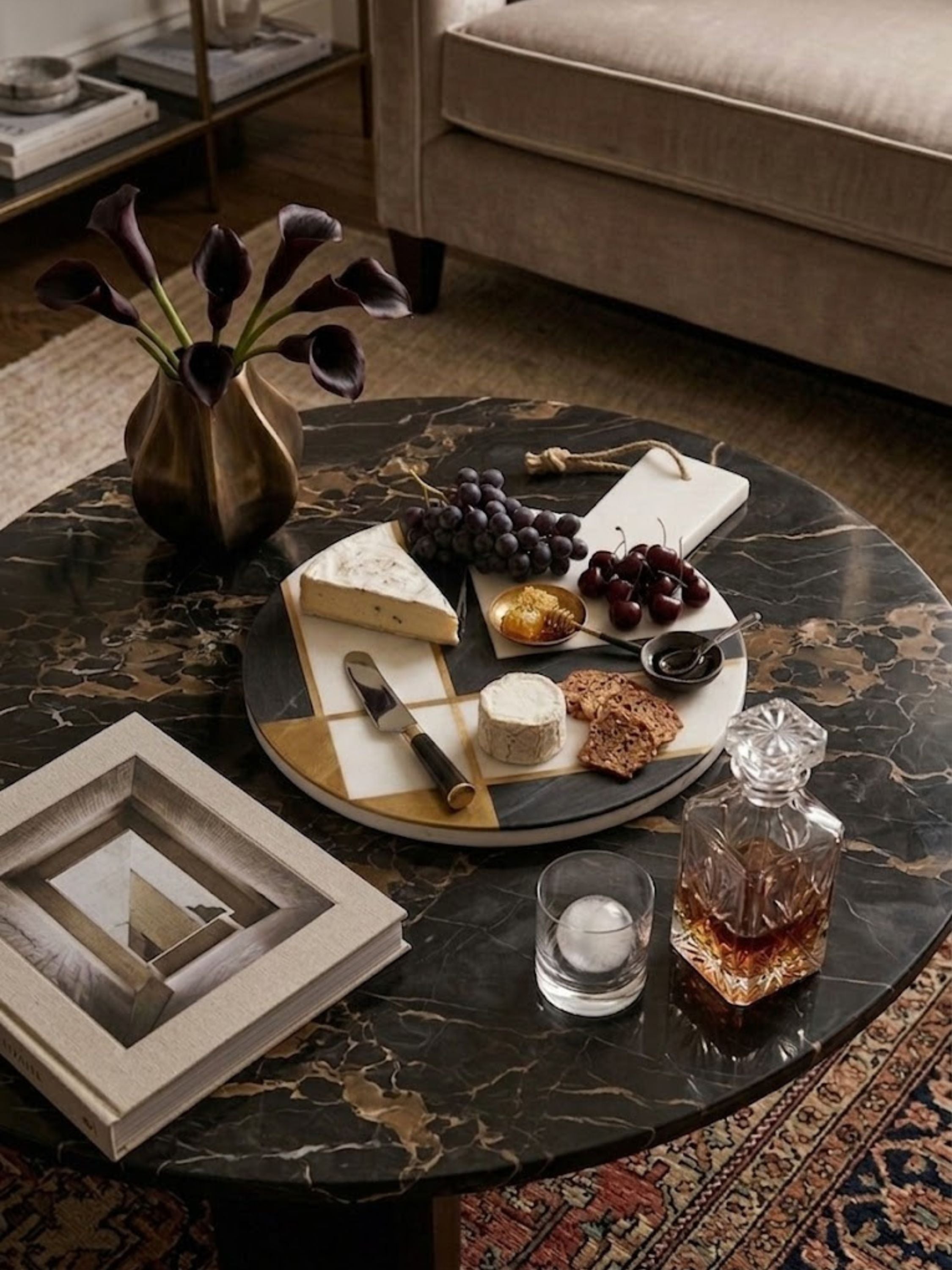 White and charcoal marble cheese board with a jute cord handle, styled in a living room.