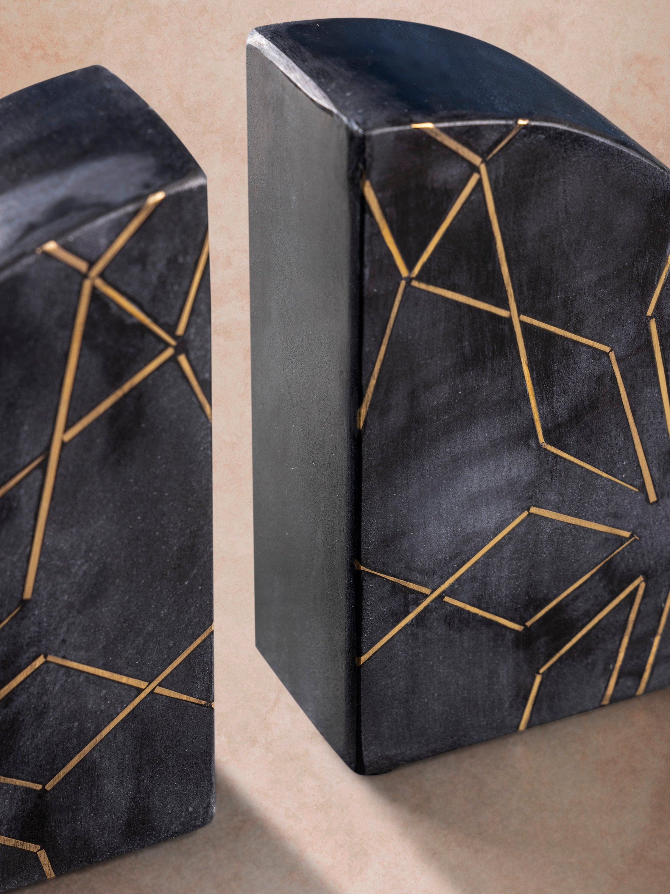 Close-up of midnight black marble bookends highlighting deep mineral tones, smooth polished surface, and delicate brass inlay pattern