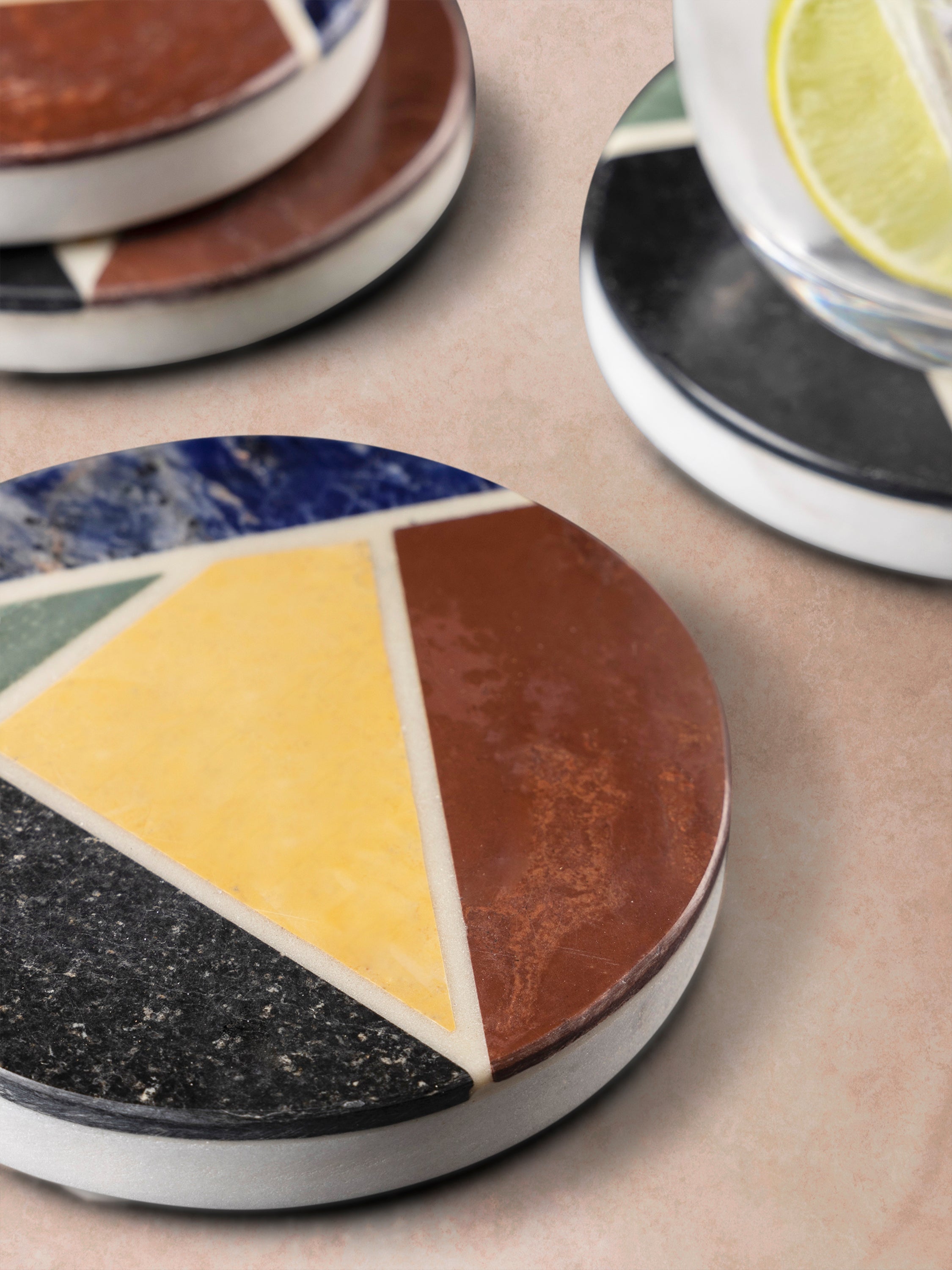 Close-up of marble coaster showing triangular inlay segments with smooth polished finish and subtle tonal variation in the stone